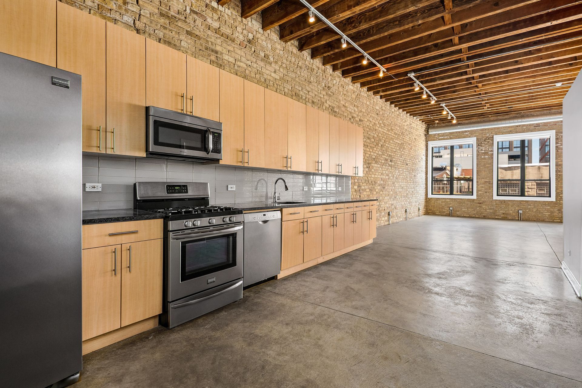 A kitchen with stainless steel appliances and wooden cabinets at 945 W Fulton Market Apartments.