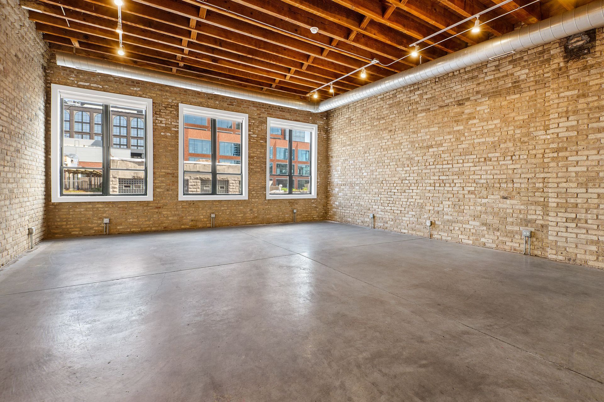 A large empty room with brick walls and concrete floors at 945 W Fulton Market Apartments.