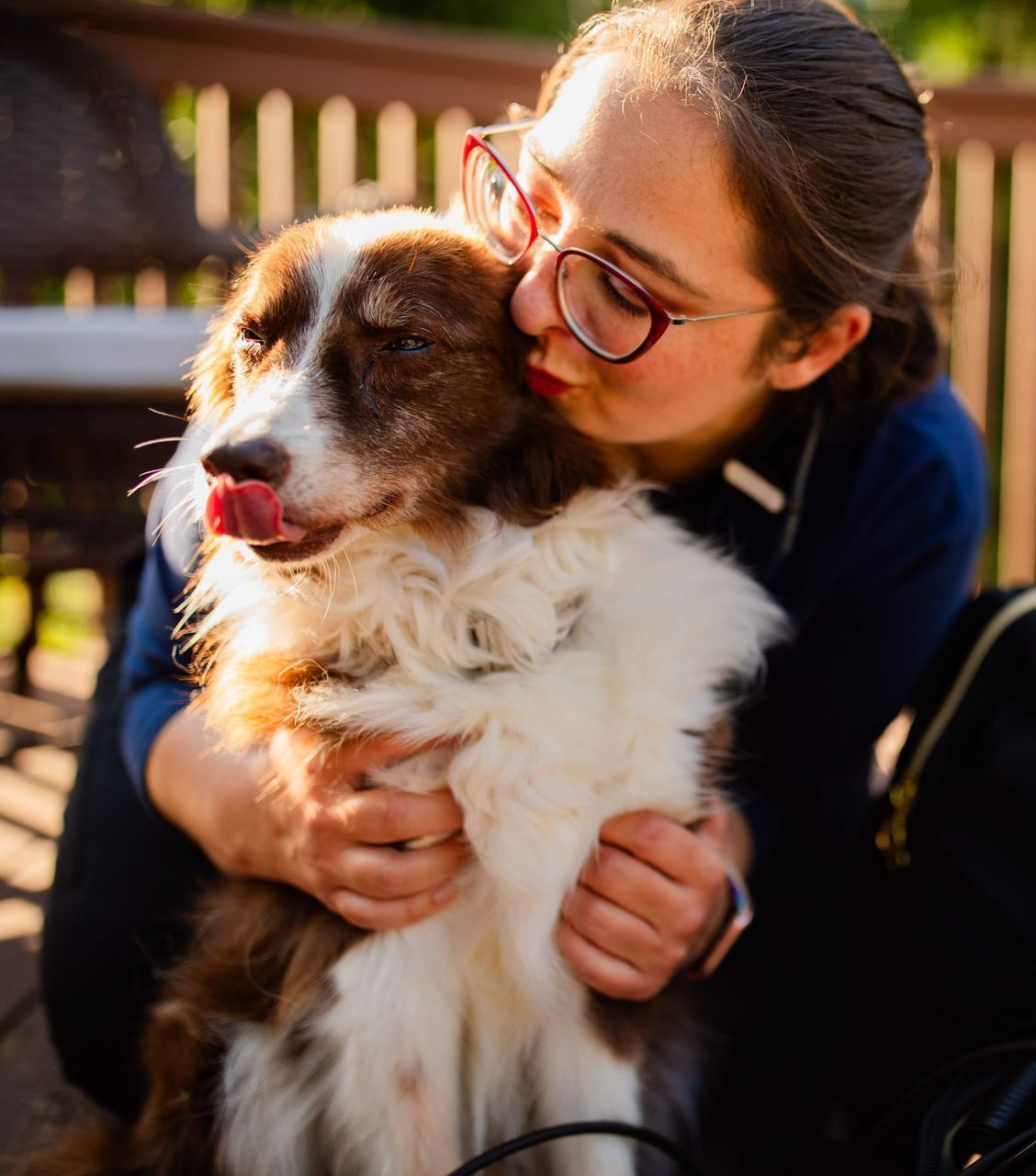 Dr. Jessi Turner is holding a brown and white dog with its tongue out .