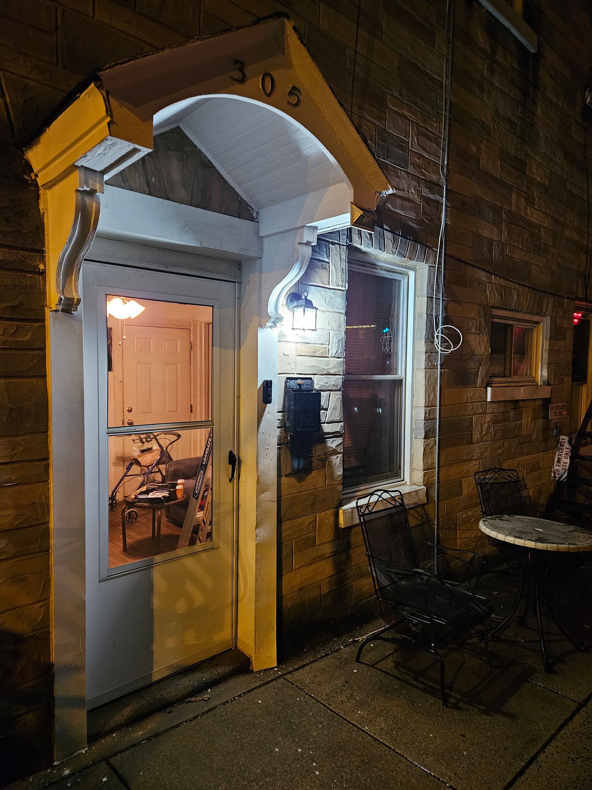 A brick building with a white door and a window at night.