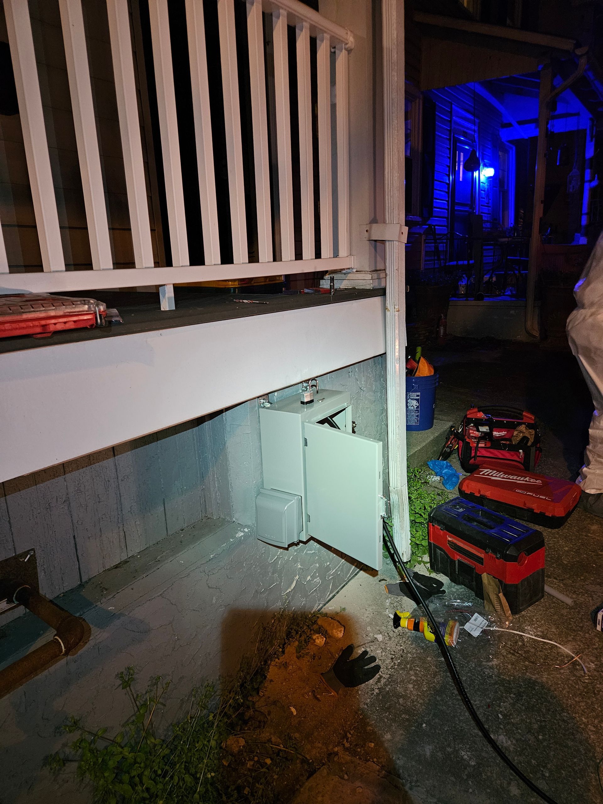 A person is working on a washing machine outside of a house at night.