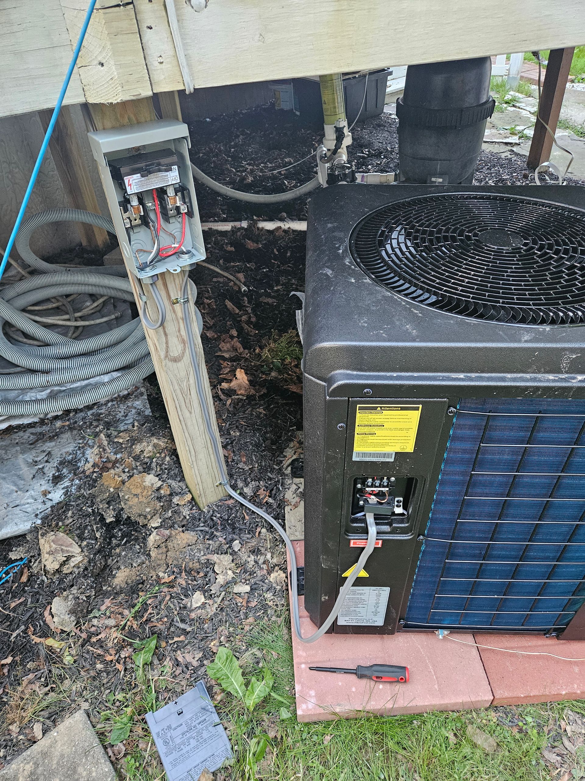 A black air conditioner is sitting on top of a brick floor.