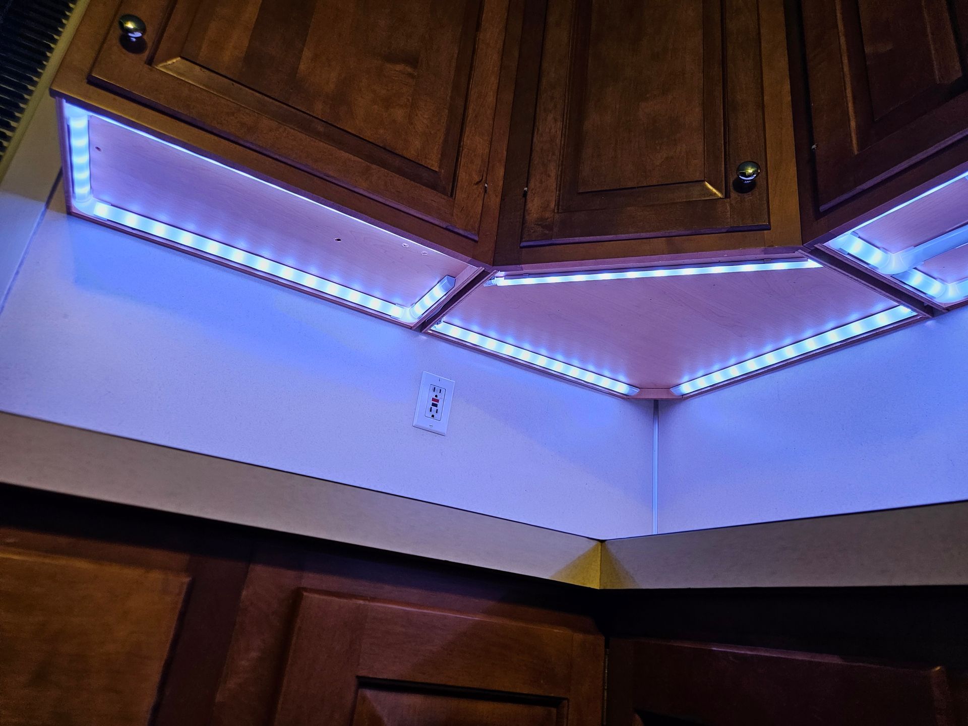 A kitchen with wooden cabinets and blue lights on the ceiling