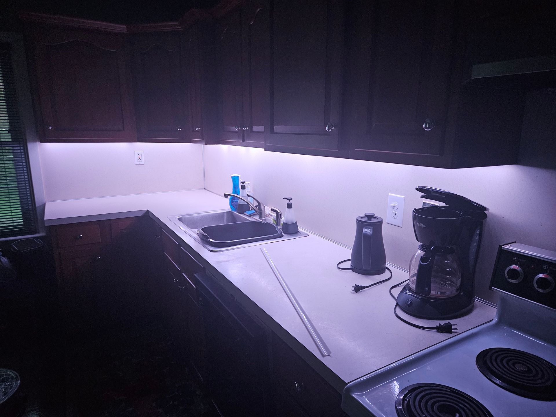 A kitchen with a sink , stove , and coffee maker.