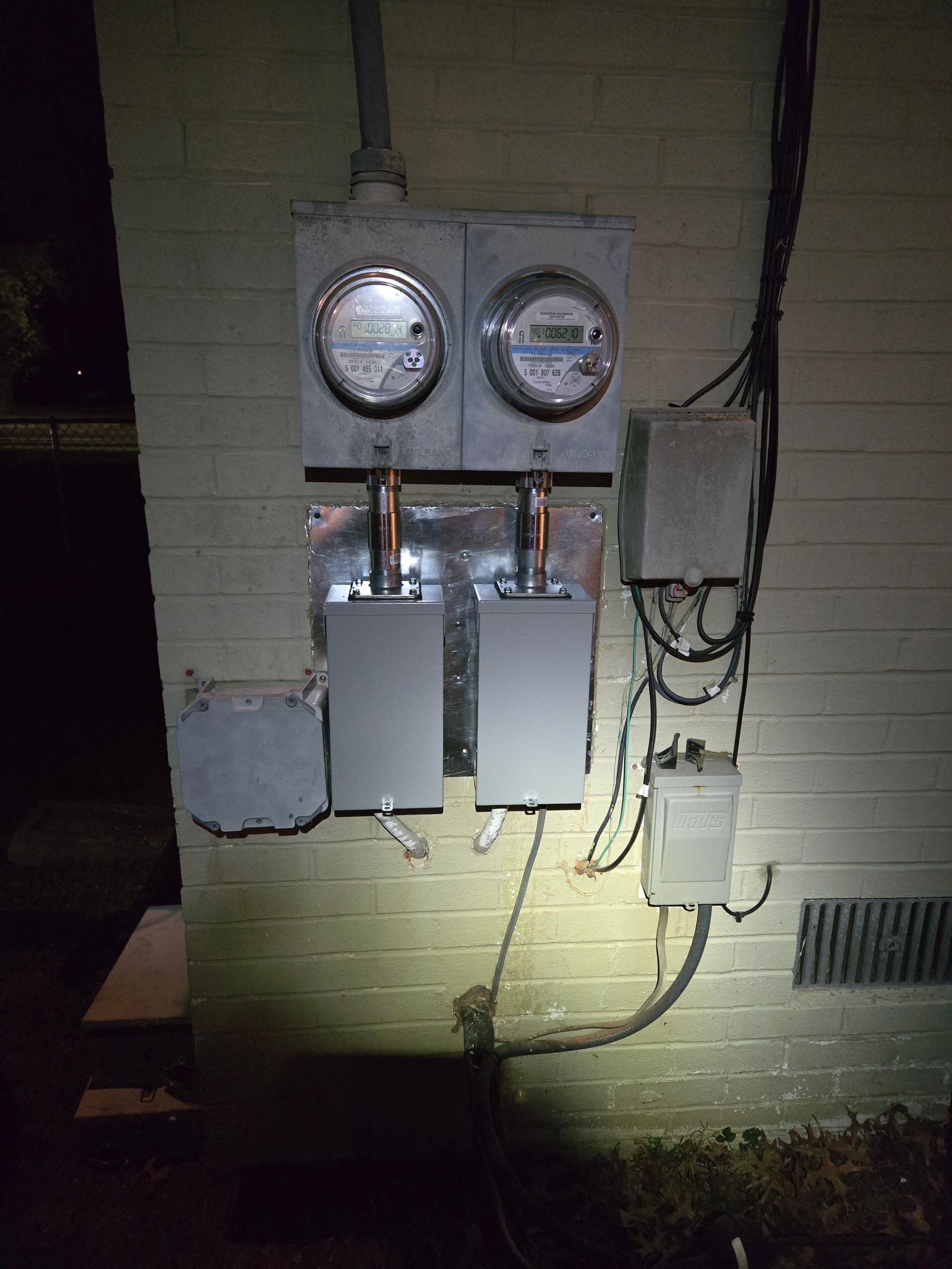 A brick wall with a bunch of electrical boxes and meters on it.