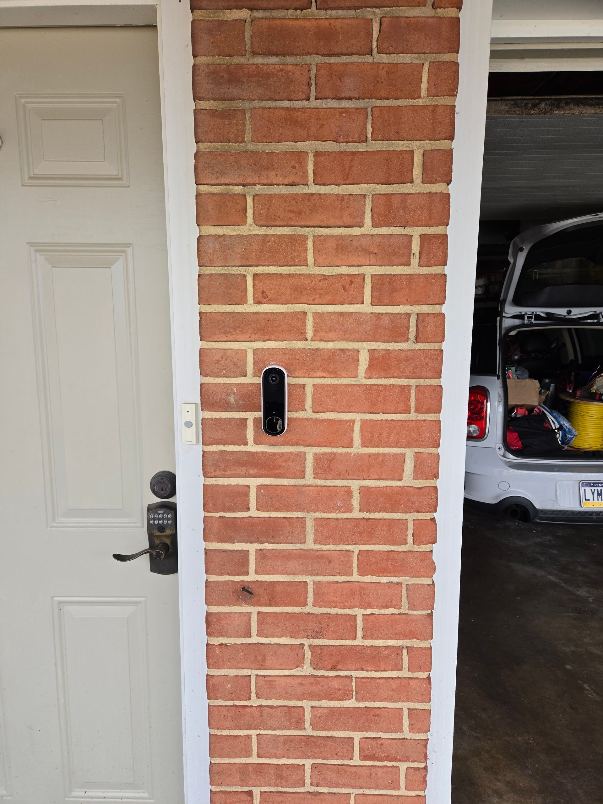 A brick wall with a door and a car in the background