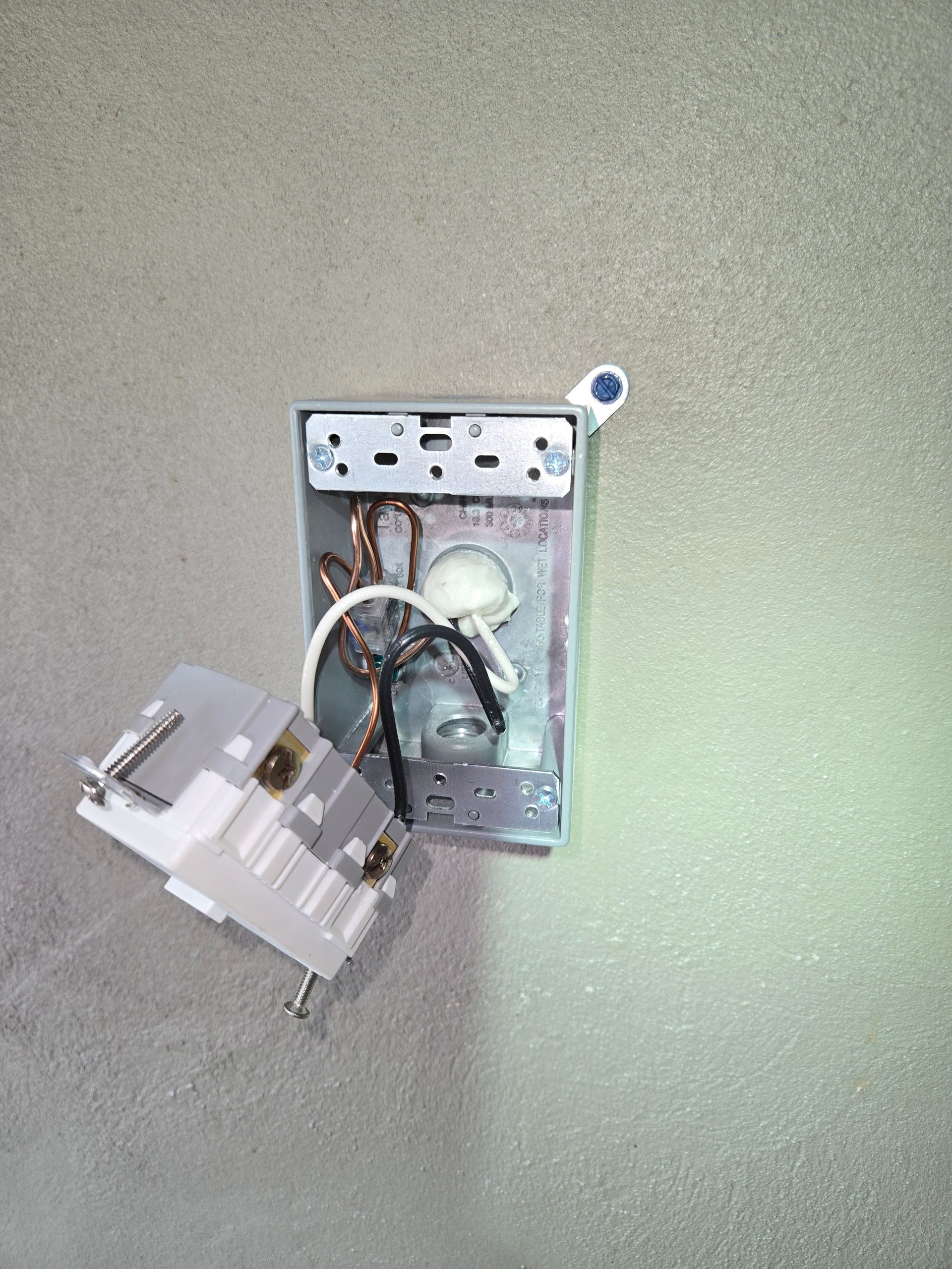 A close up of a broken electrical outlet on a wall.
