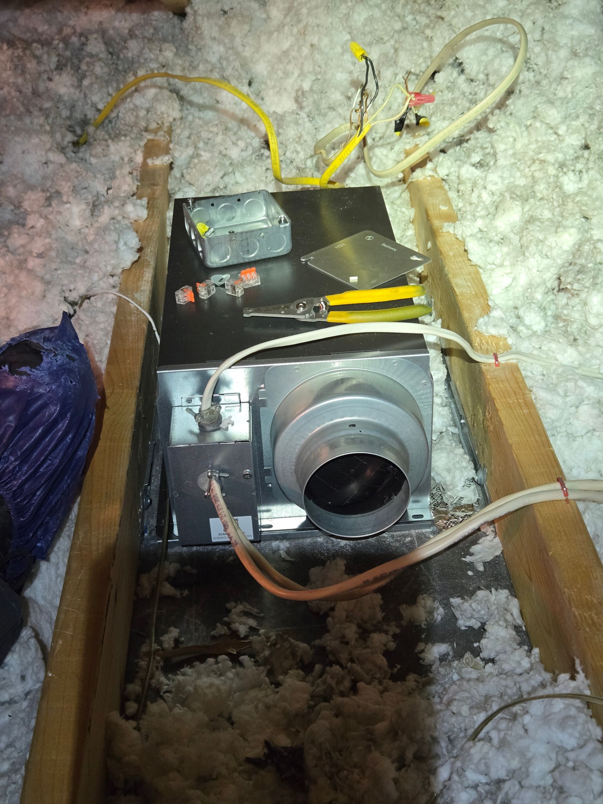 A box with wires coming out of it is in the attic.