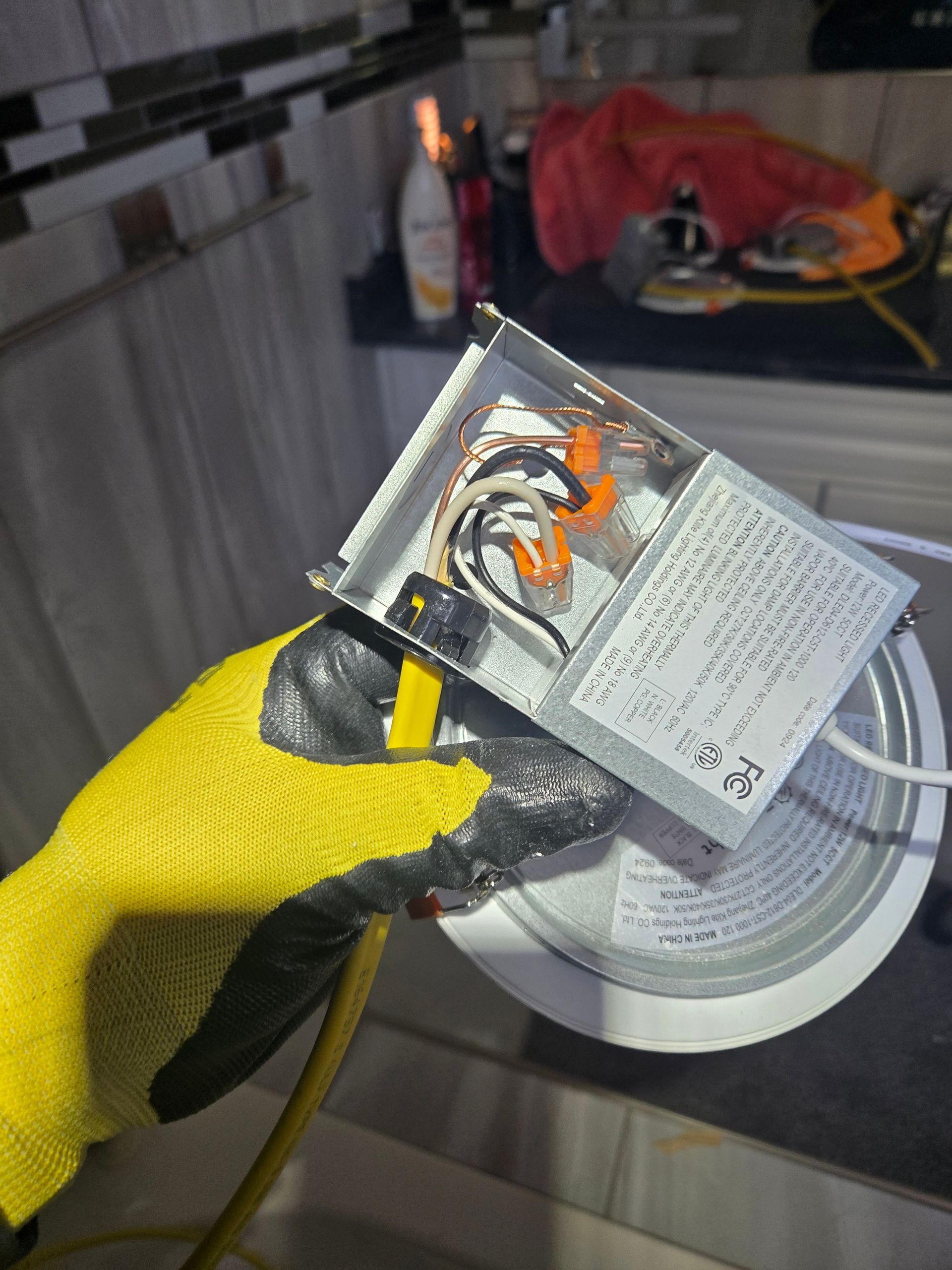 A person wearing yellow gloves is holding a box of wires.