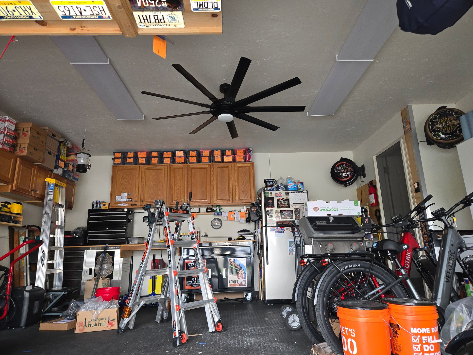 A garage with a ceiling fan and two orange buckets that say 50