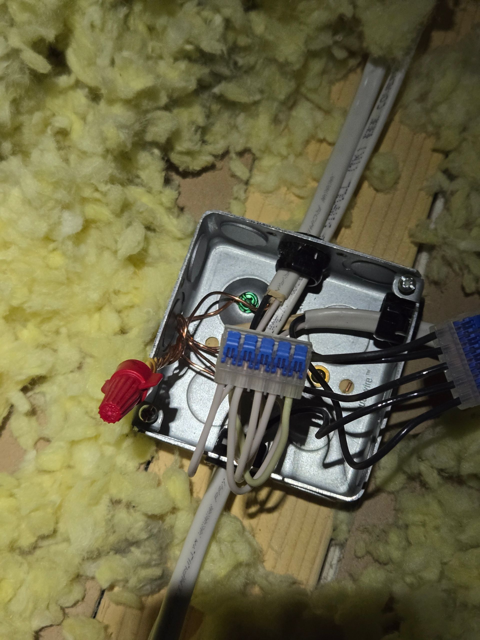 A metal box with wires coming out of it is sitting on a wooden floor.