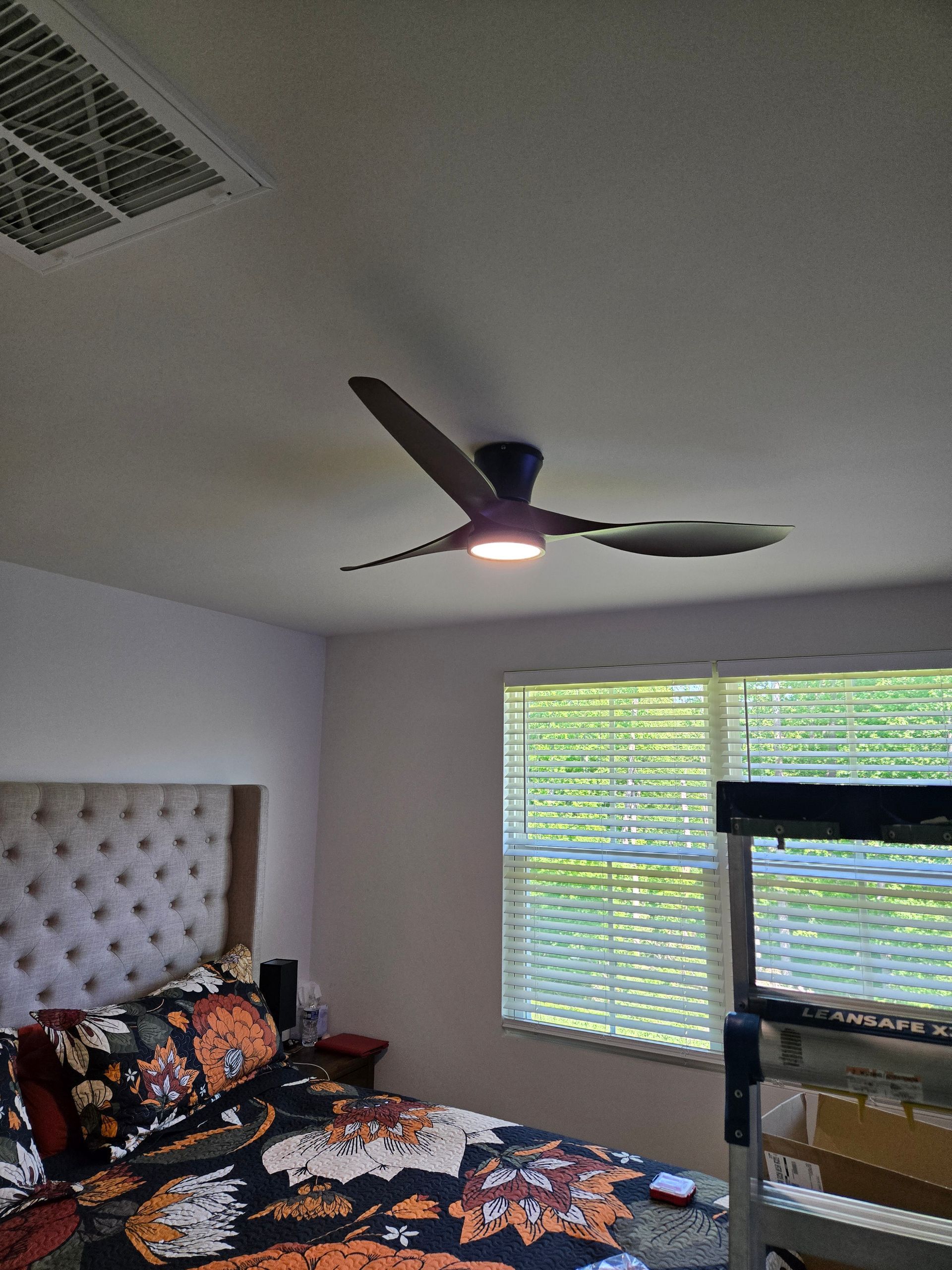 A bedroom with a bed and a ceiling fan.