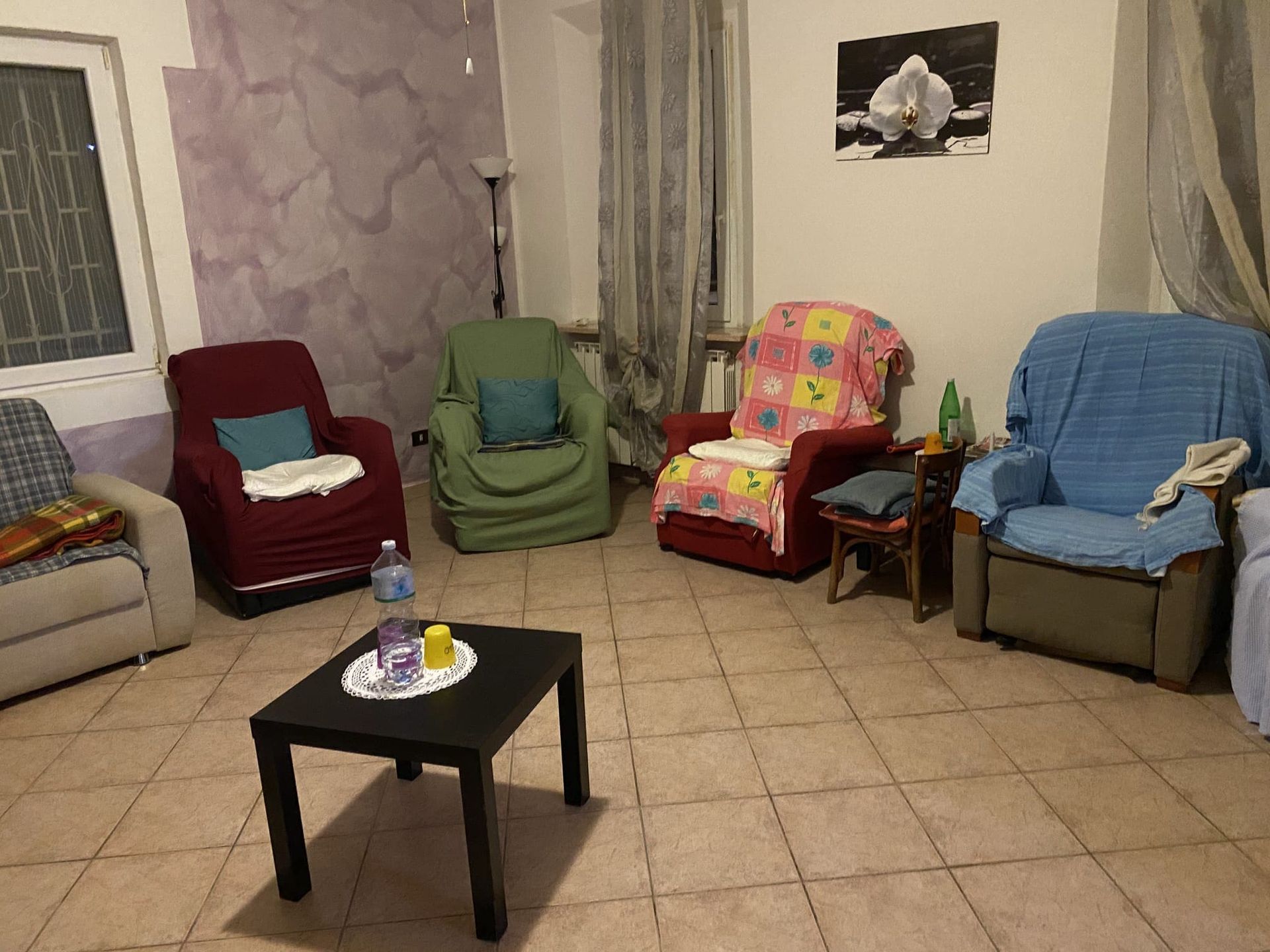 Soggiorno con poltrone spaiate, un tavolino da caffè e un quadro con un'orchidea.