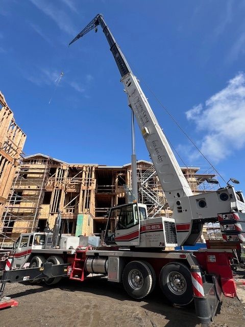 A large crane is parked in front of a building under construction.