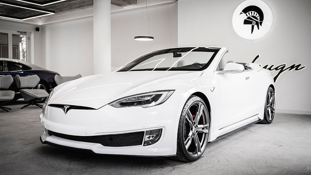 A white tesla model s convertible is parked in a garage.