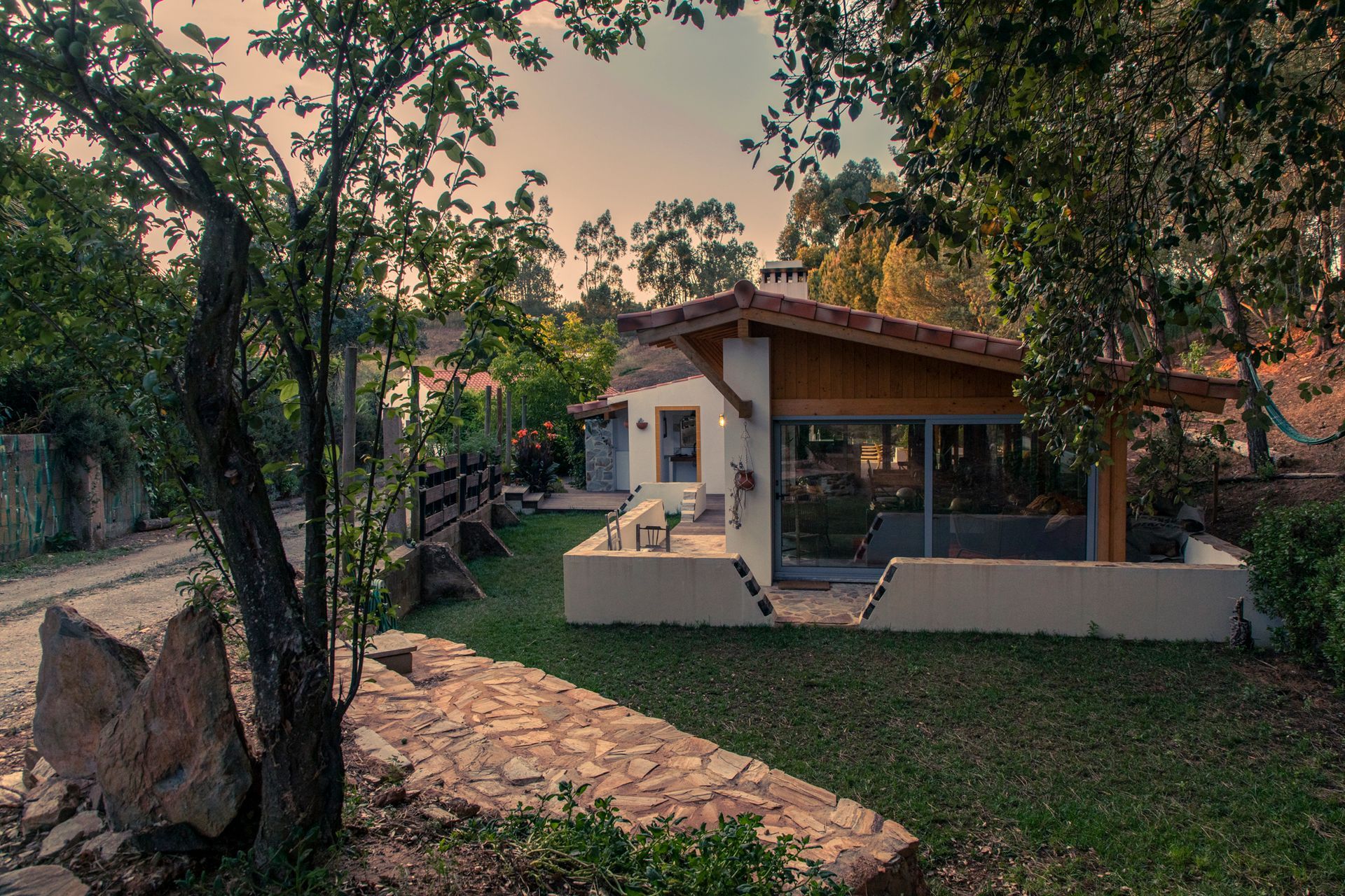 Aerial view of a white mansion surrounded by green fields and trees under a cloudy blue sky.