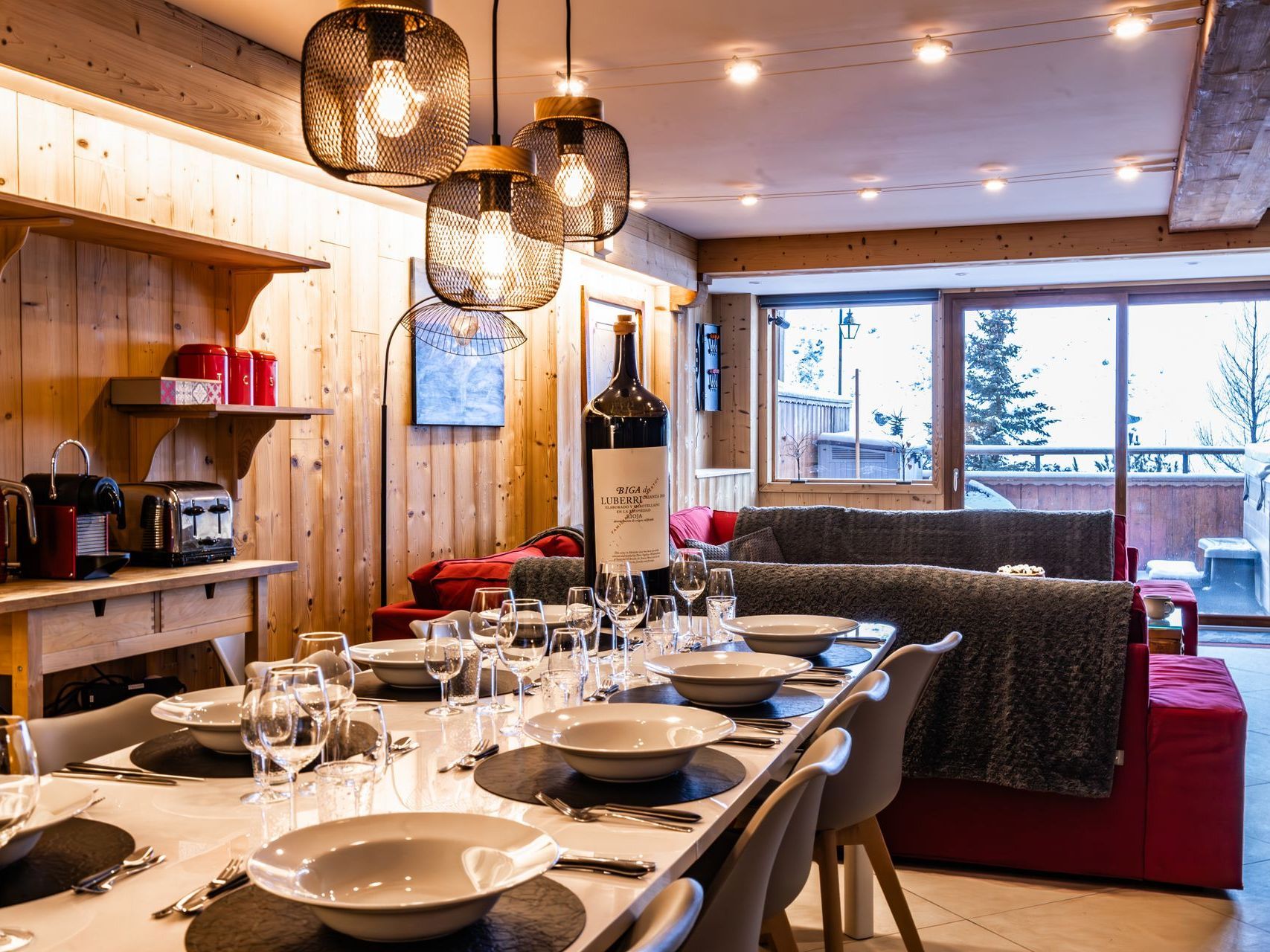 A dining room table with plates , glasses , and a bottle of wine.