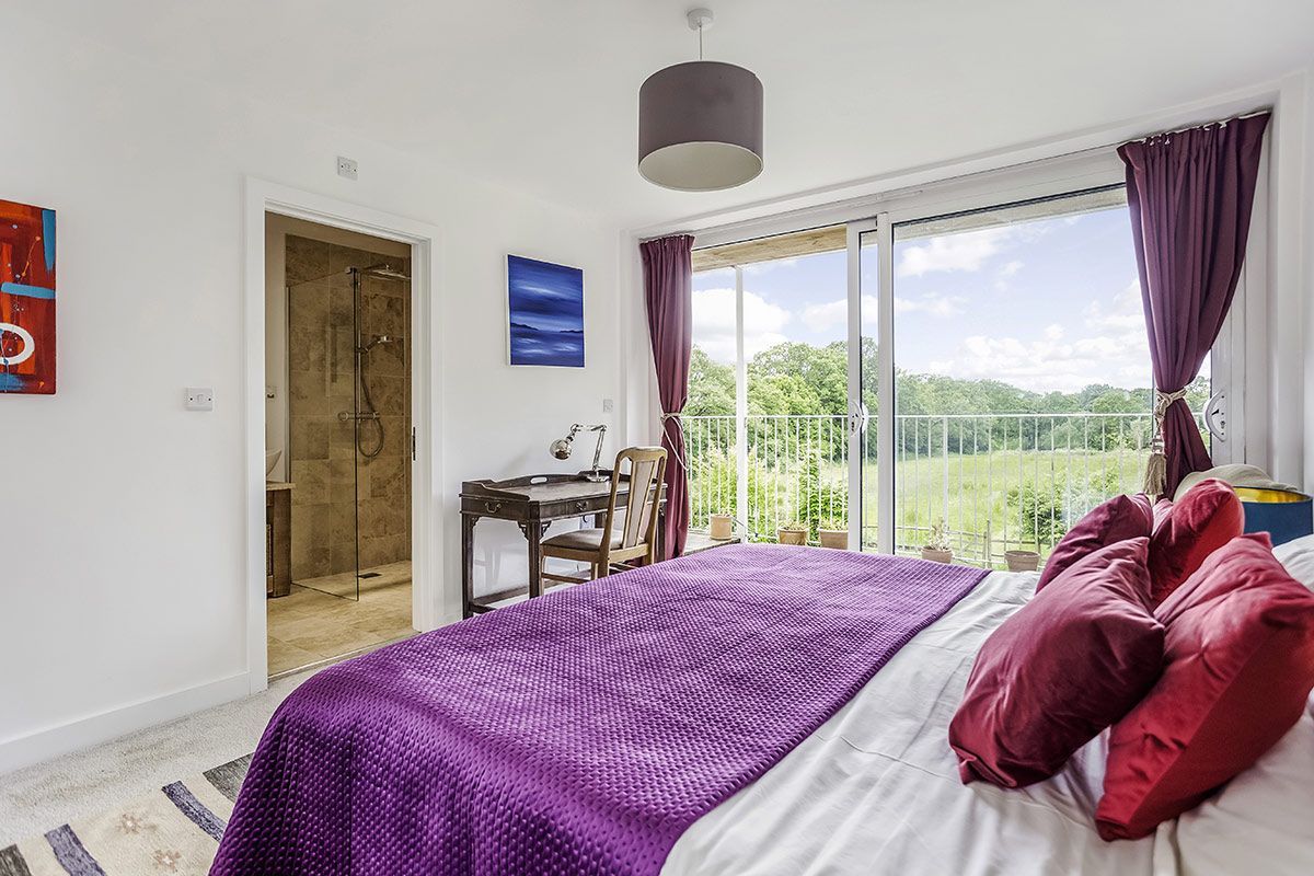 Bedroom with purple bedspread, red pillows, sliding glass door to a balcony, and a doorway to a bathroom.