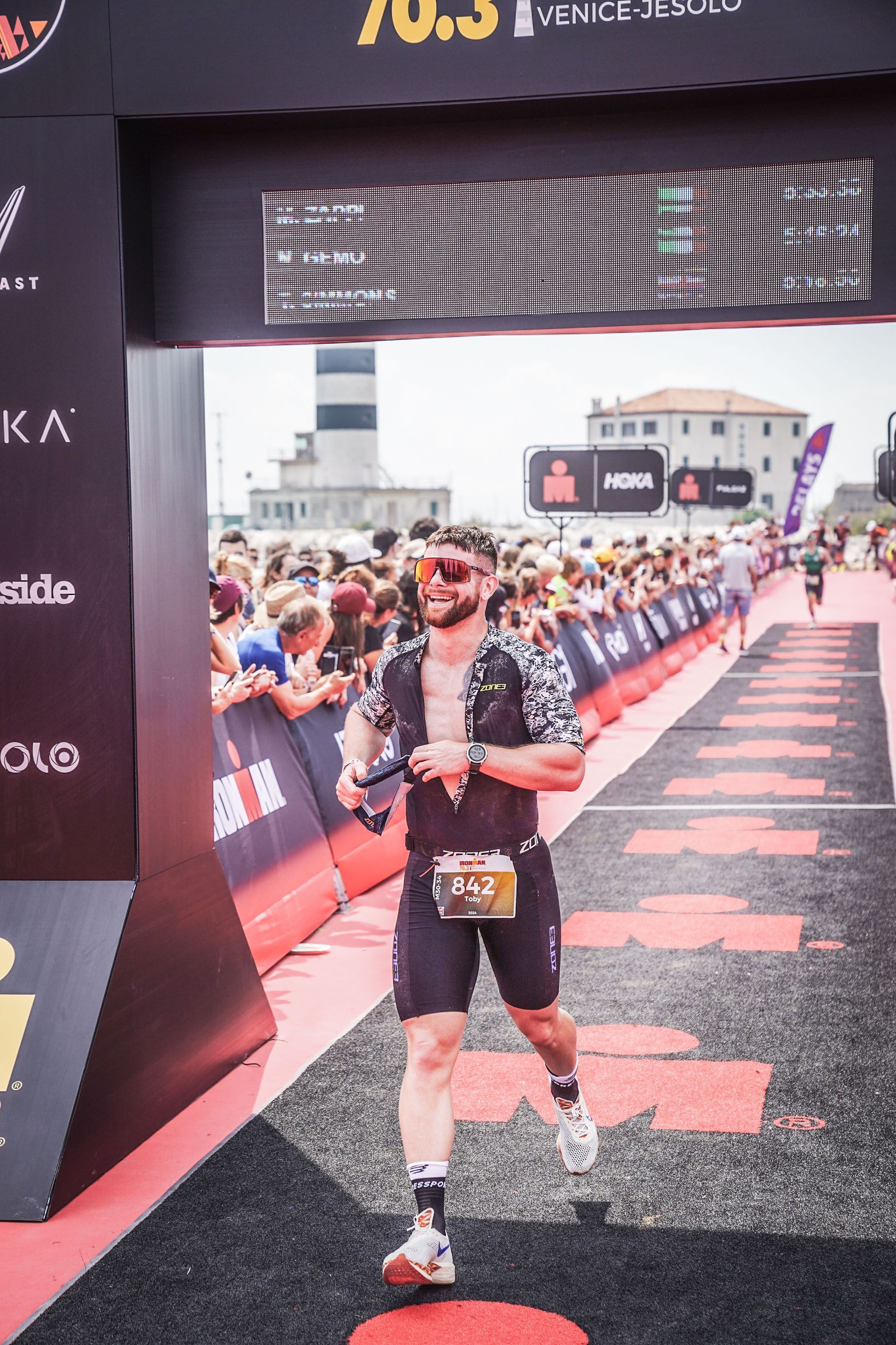 A man is standing in front of a crowd at a race.