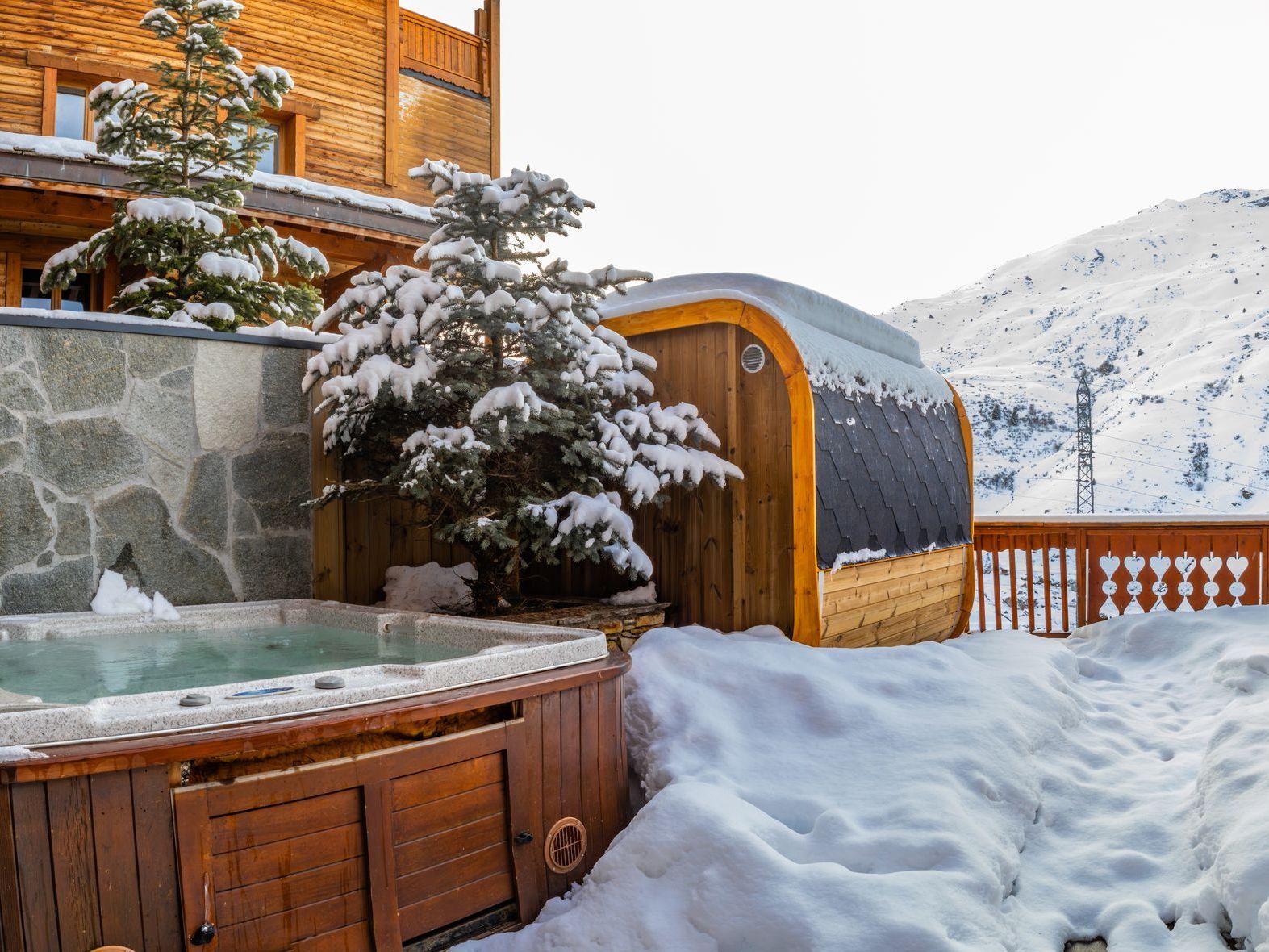 A hot tub is sitting in the snow in front of a building.