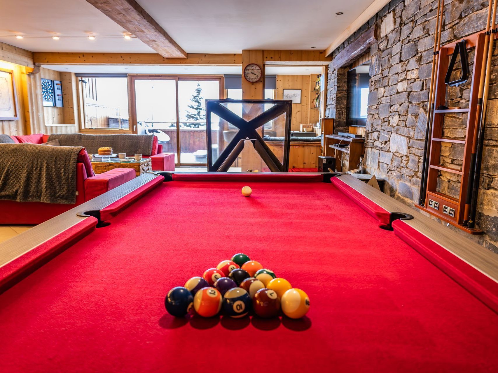 A pool table filled with pool balls in a living room.