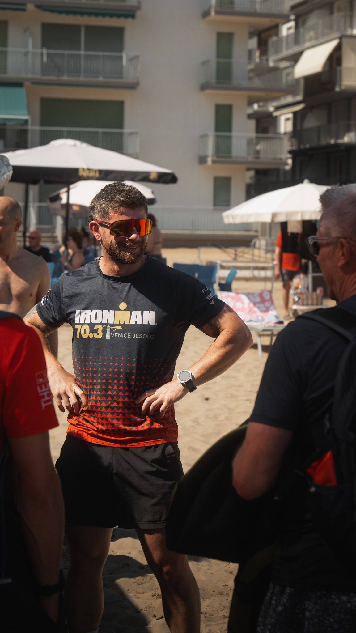 A group of men are standing on a beach talking to each other.