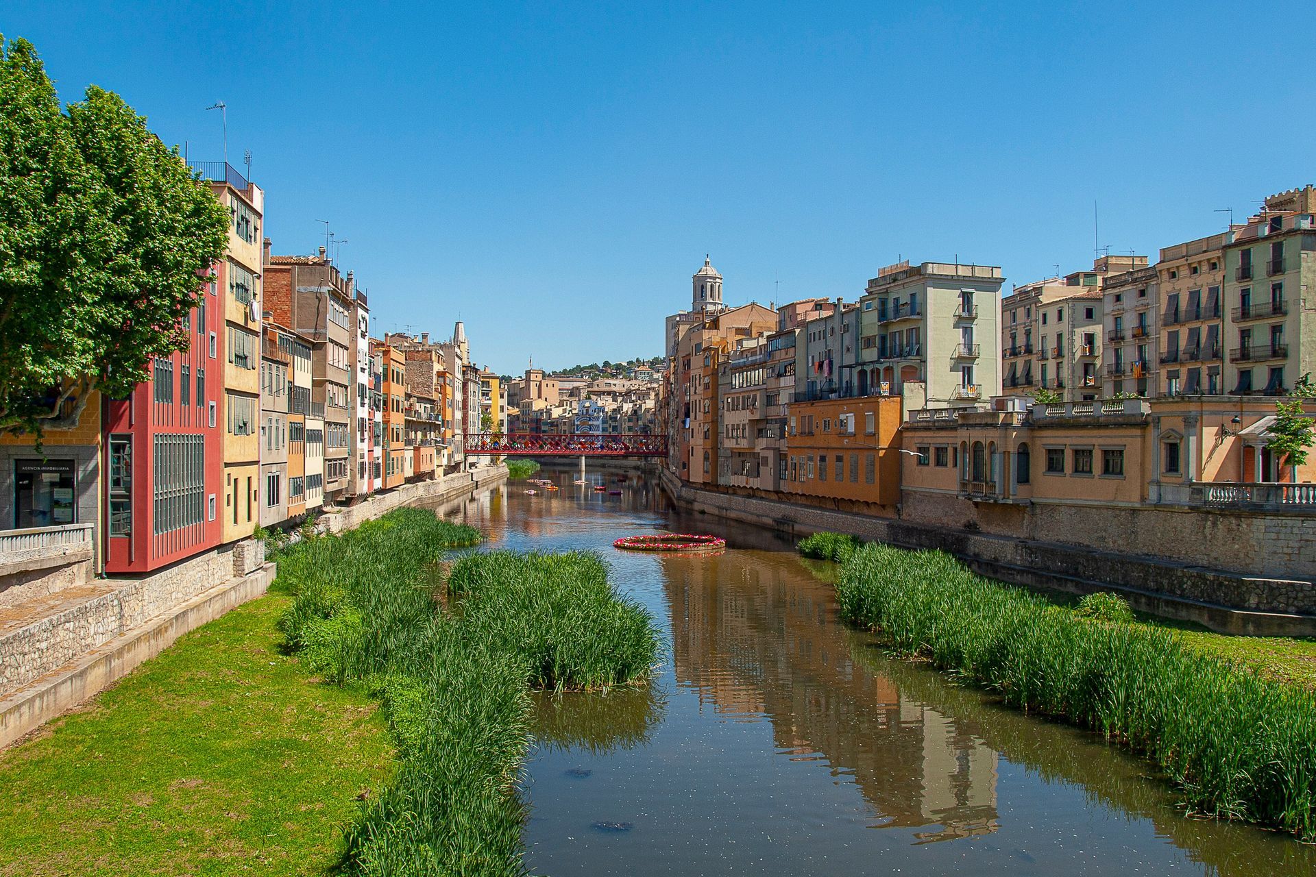 A river runs through a city surrounded by buildings on a sunny day.