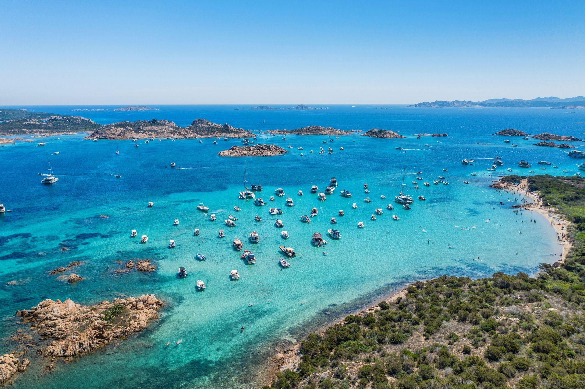 An aerial view of a tropical beach with lots of boats in the water.