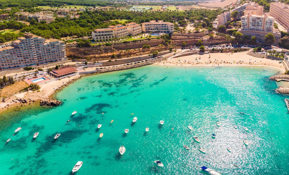 An aerial view of a beach with boats in the water.