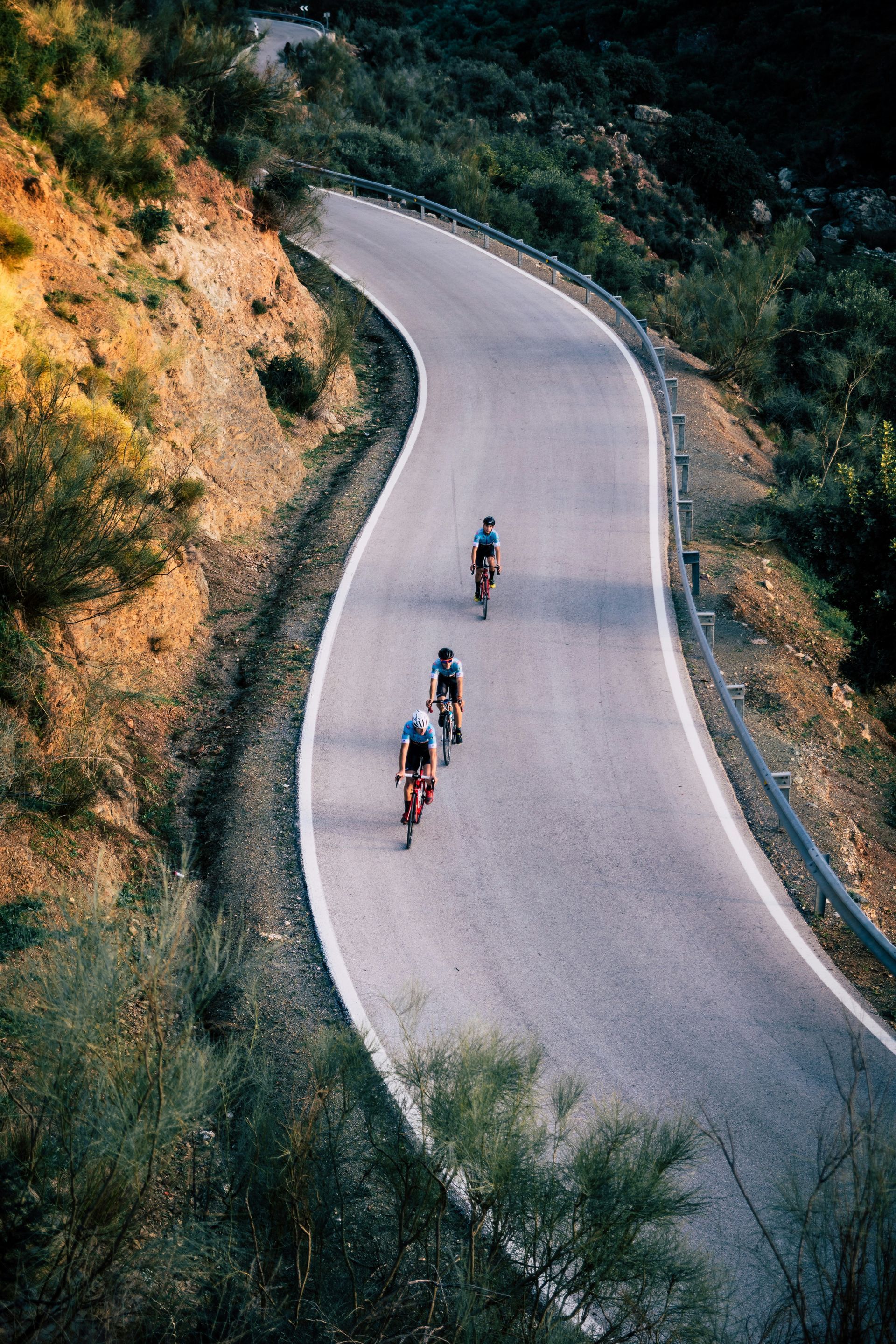 A group of people are riding bicycles down a curvy road.