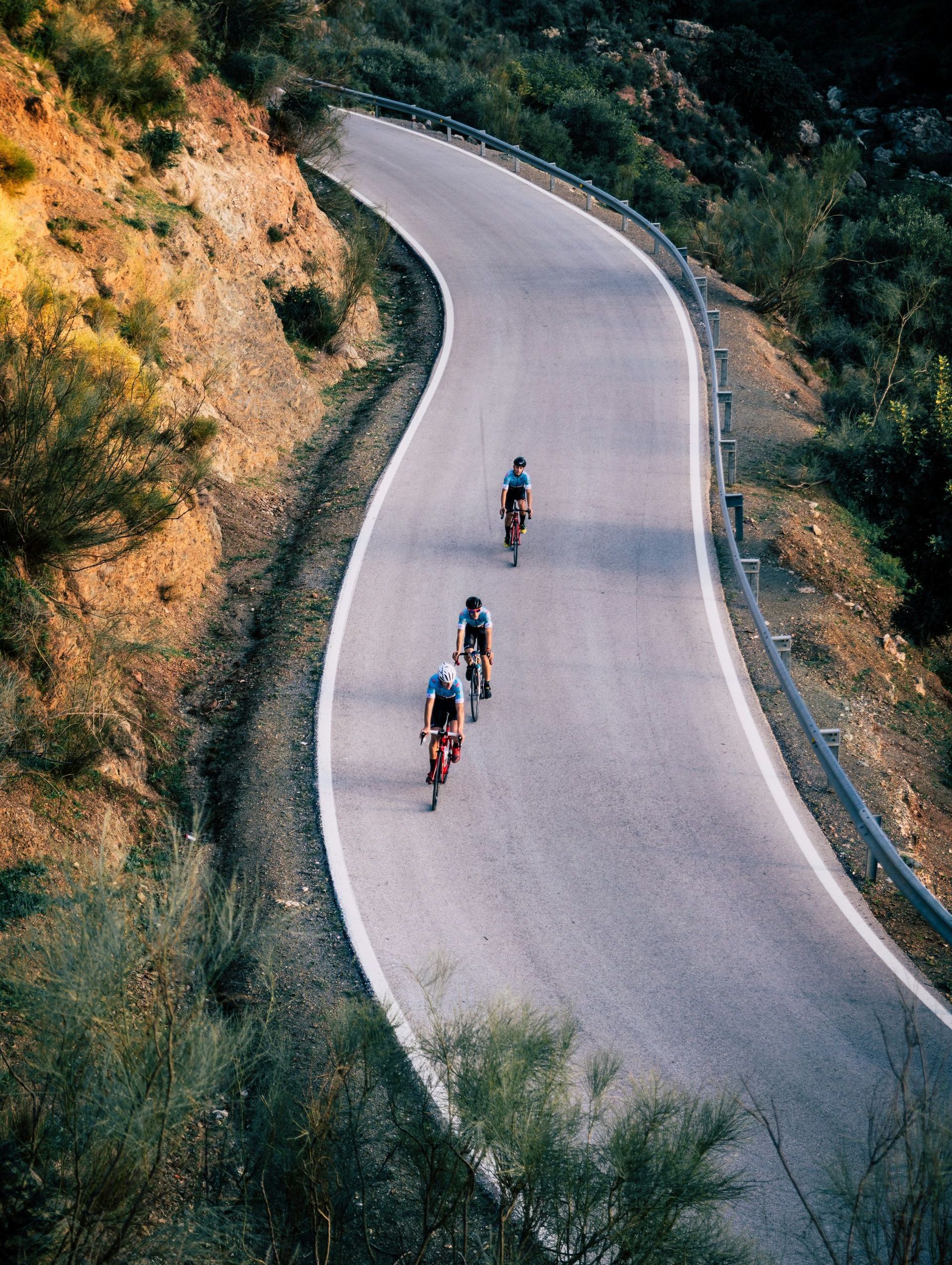 A group of people are riding bicycles down a curvy road.