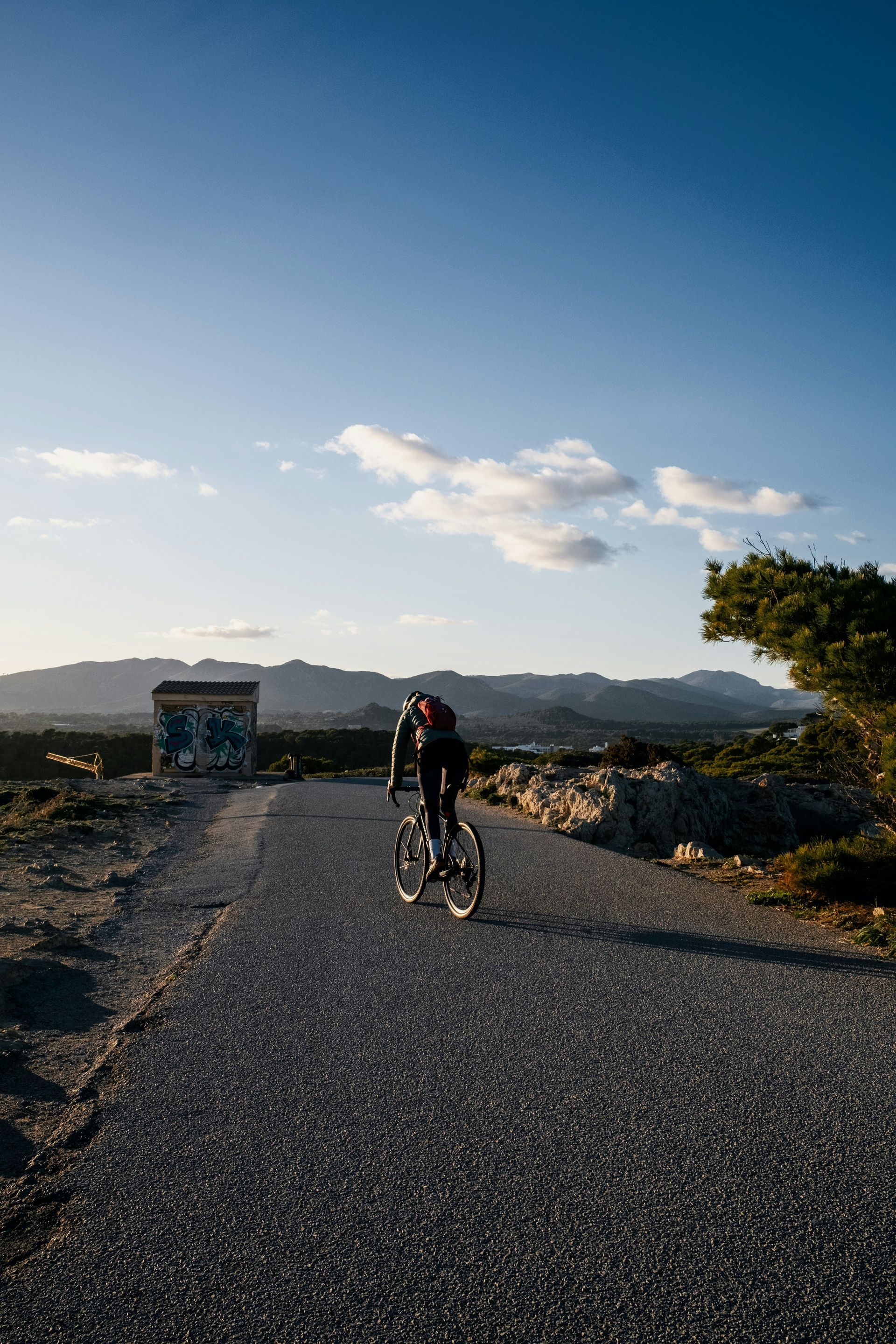 A person is riding a bike down a gravel road.