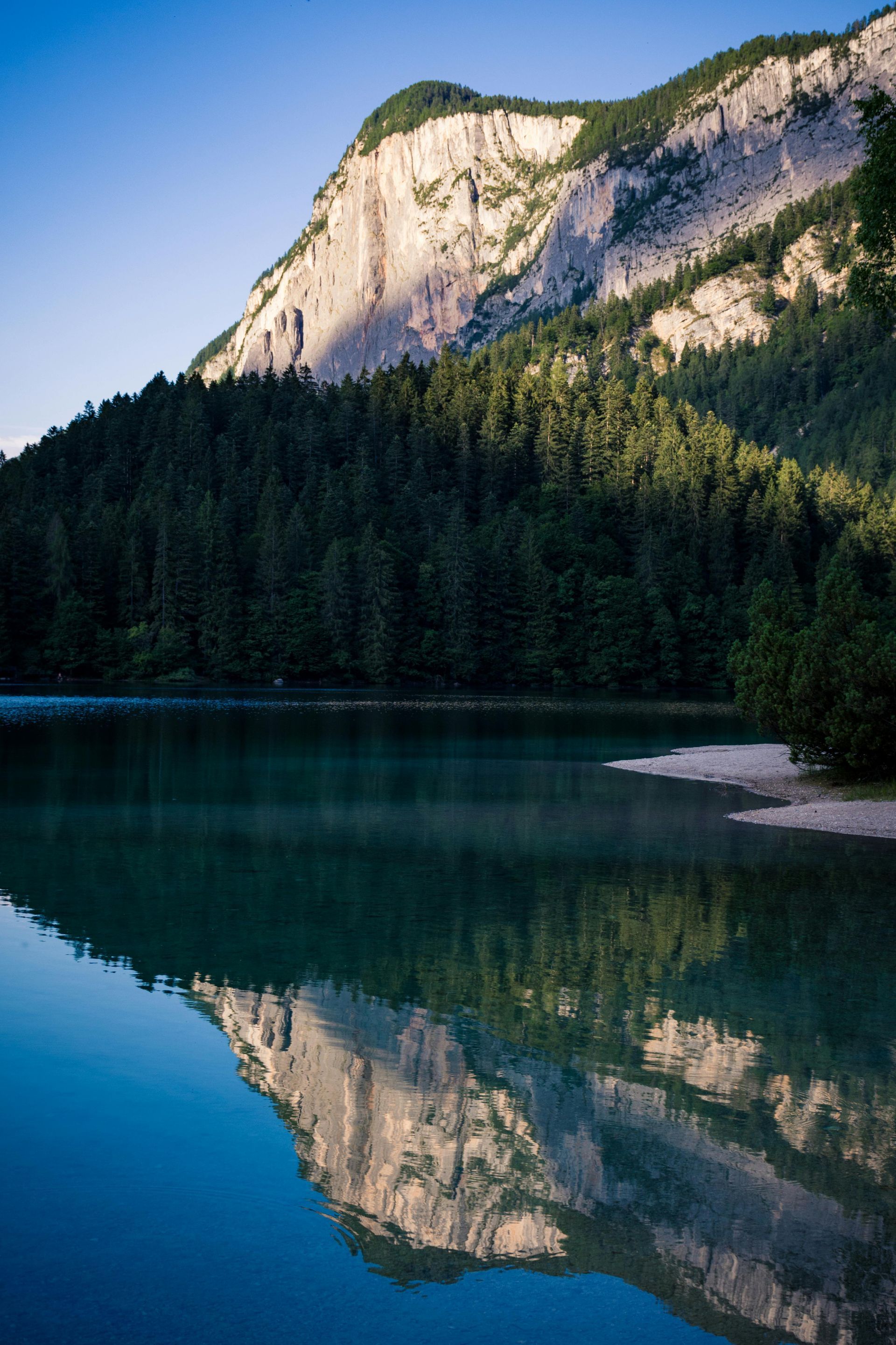 A mountain is reflected in a lake surrounded by trees.