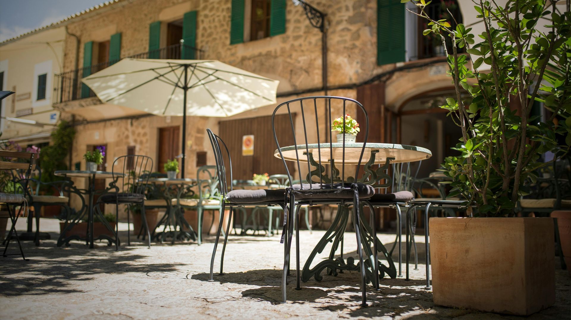 A patio with tables and chairs and umbrellas in front of a building.