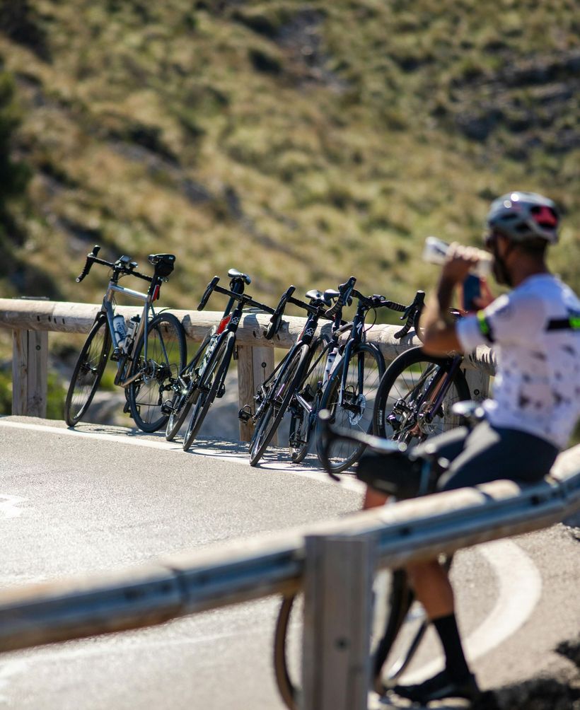 A man is taking a picture of a row of bicycles parked on the side of the road.