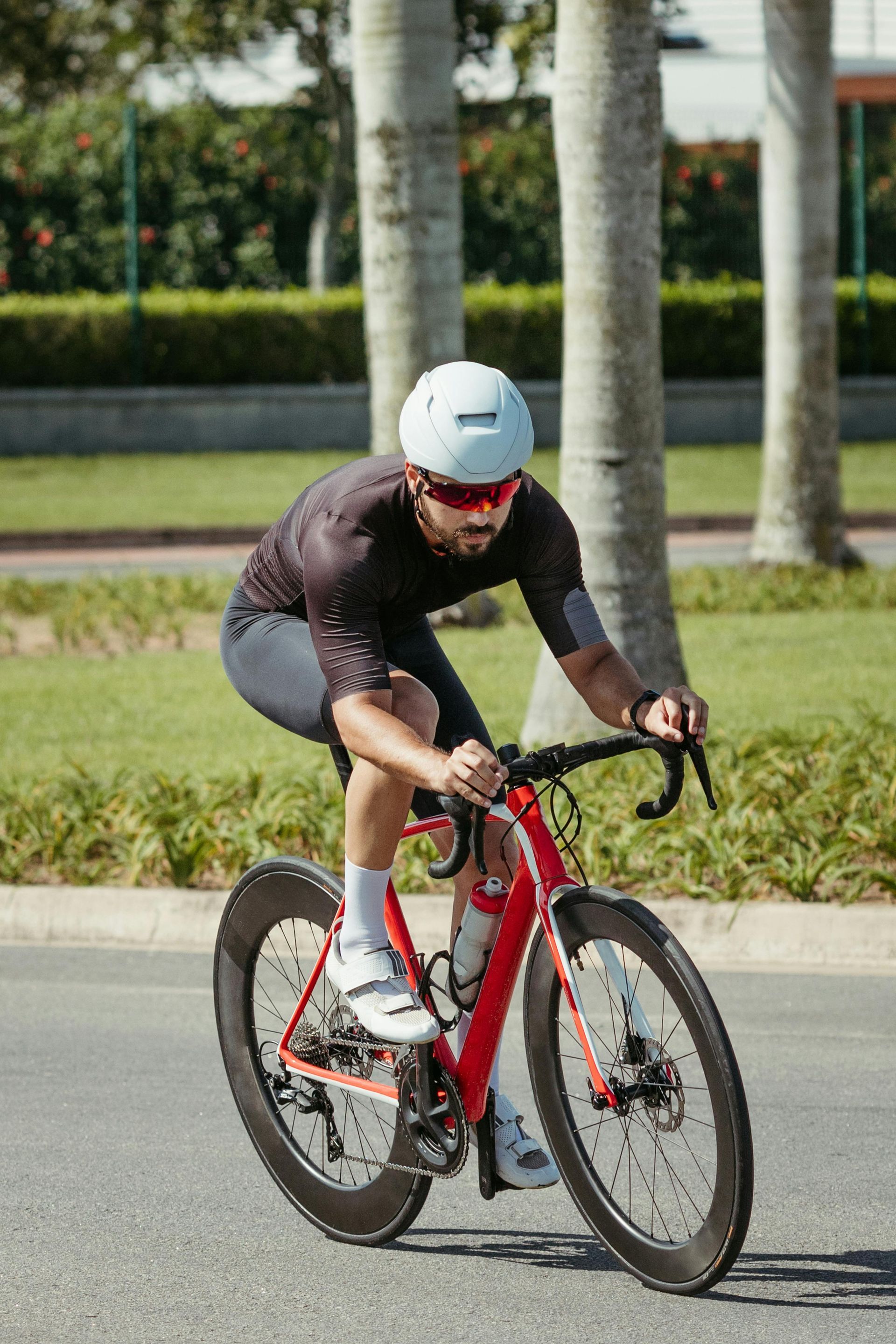 A man is riding a red bicycle down a road.