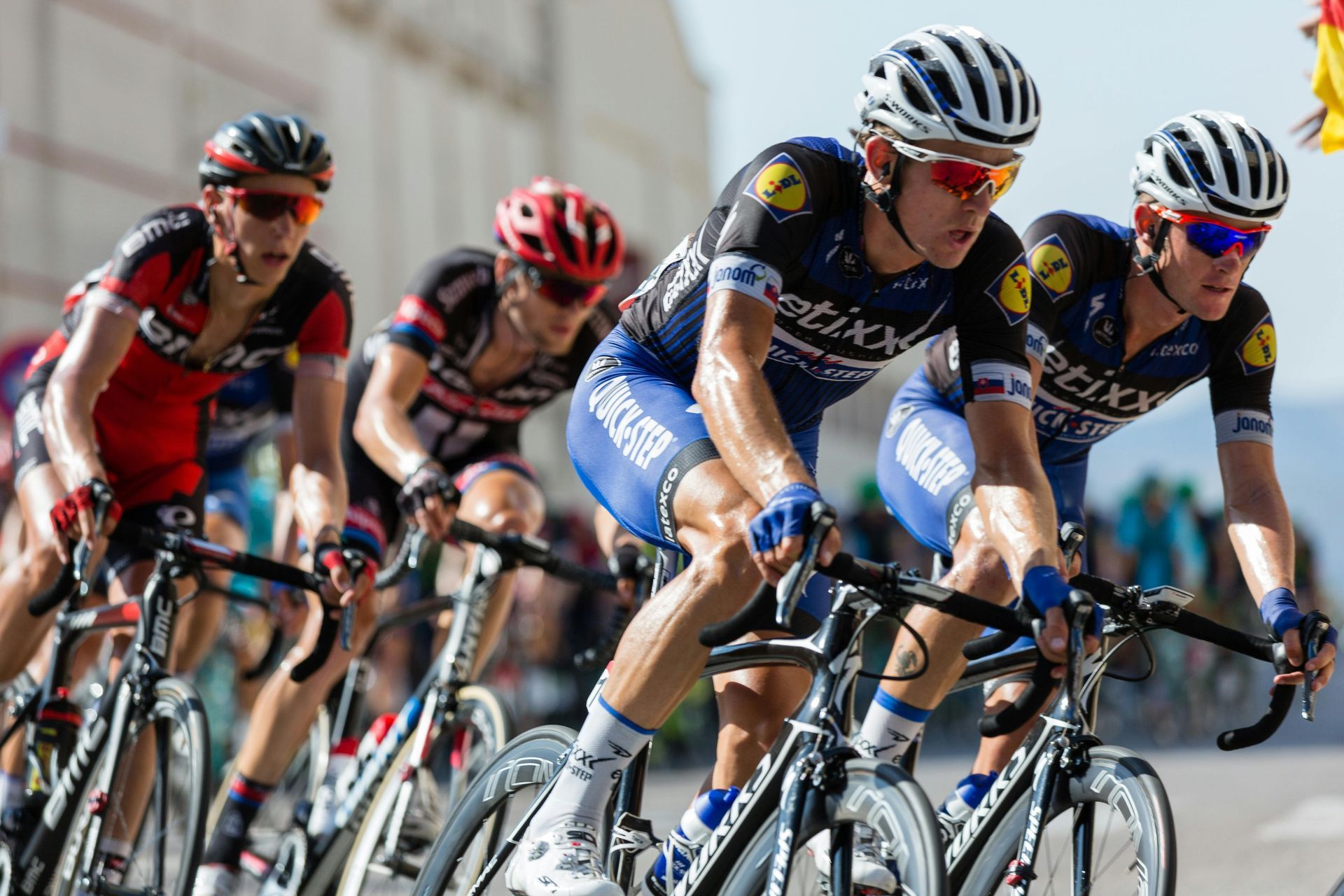 A group of men are riding bicycles down a street.