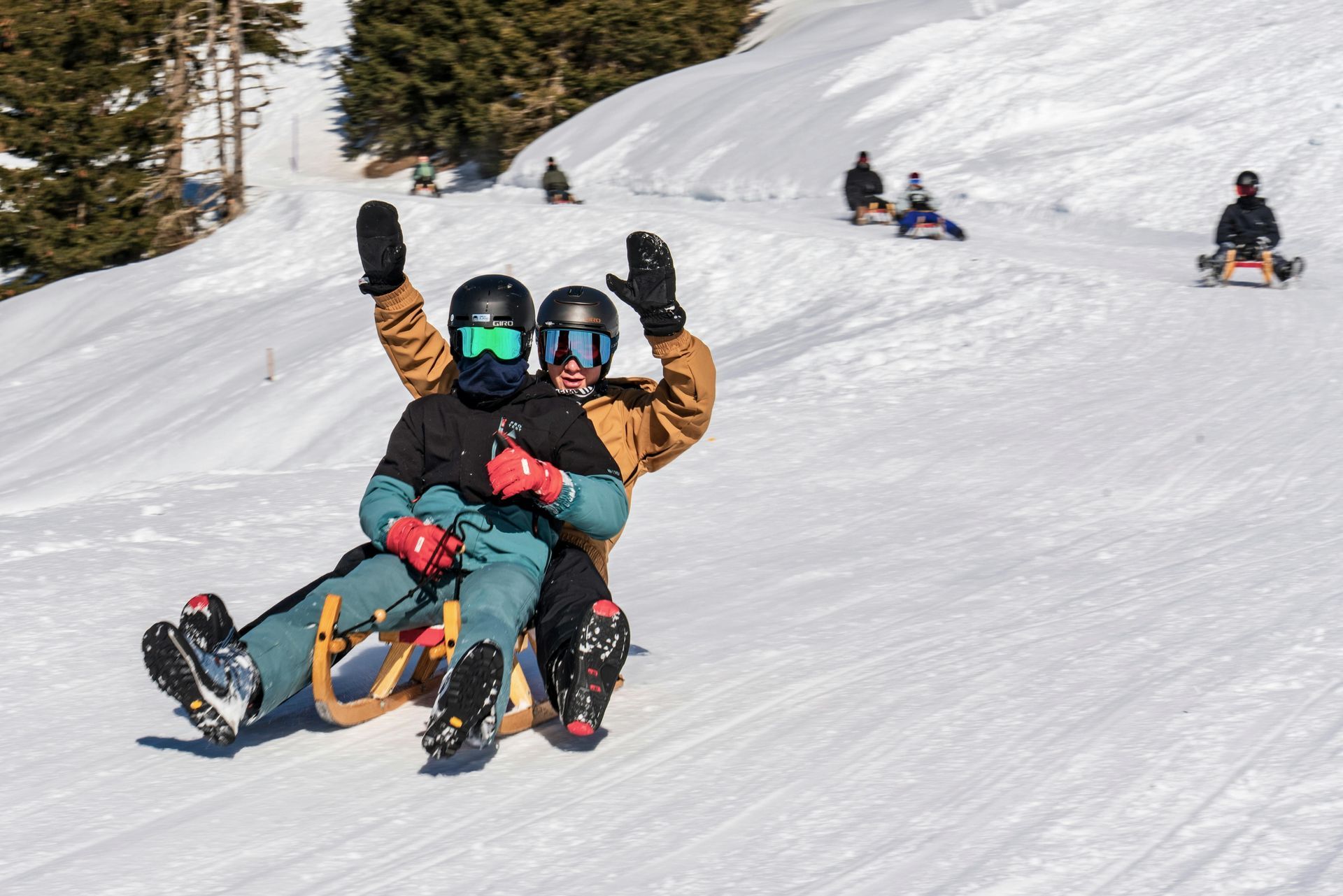 A group of people are sledding down a snow covered hill.