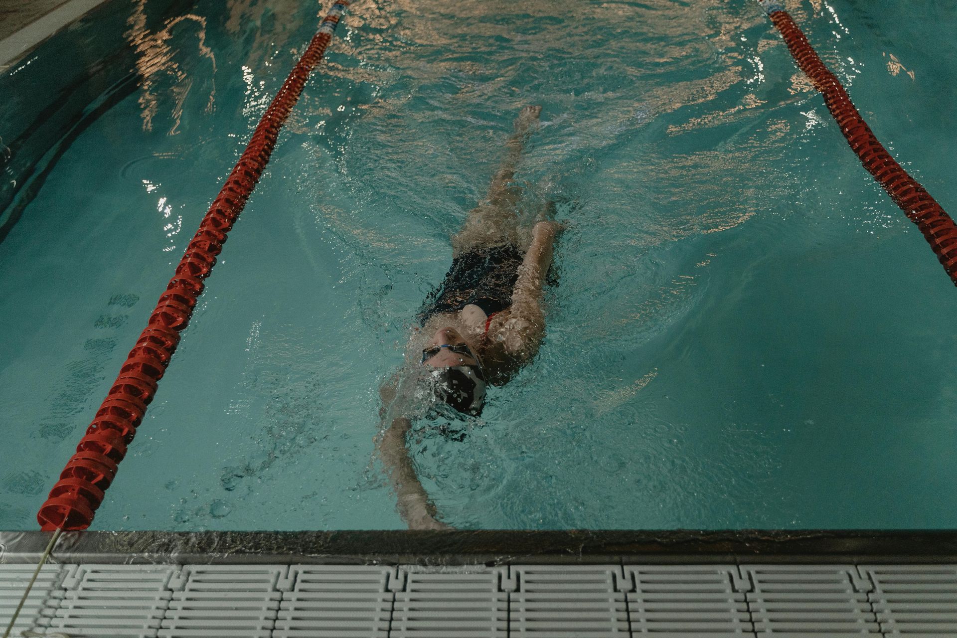 A person is swimming in a swimming pool with red lanes.