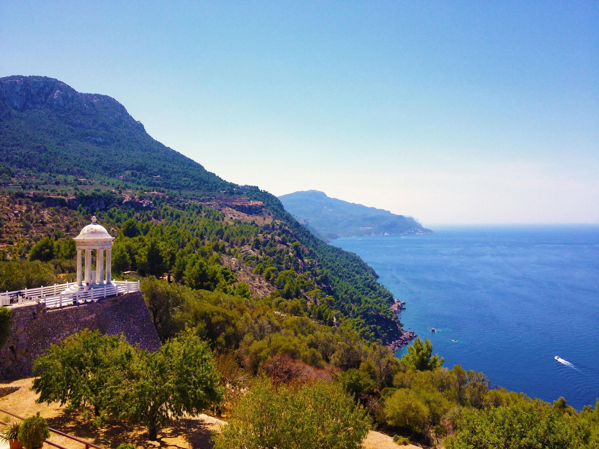 There is a gazebo on top of a hill overlooking the ocean.