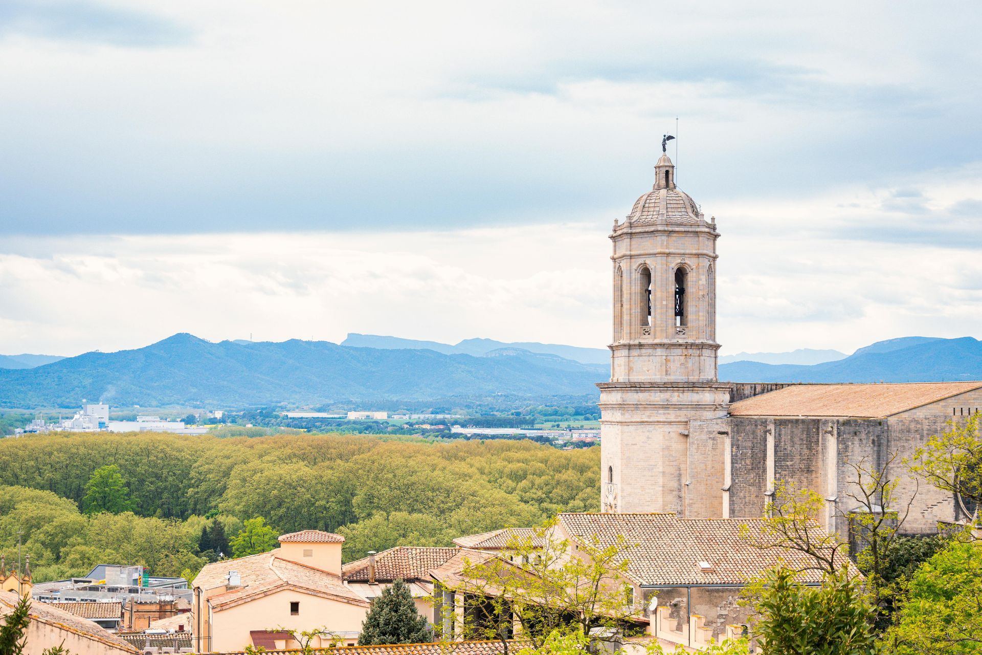 A church tower in the middle of a village with mountains in the background.