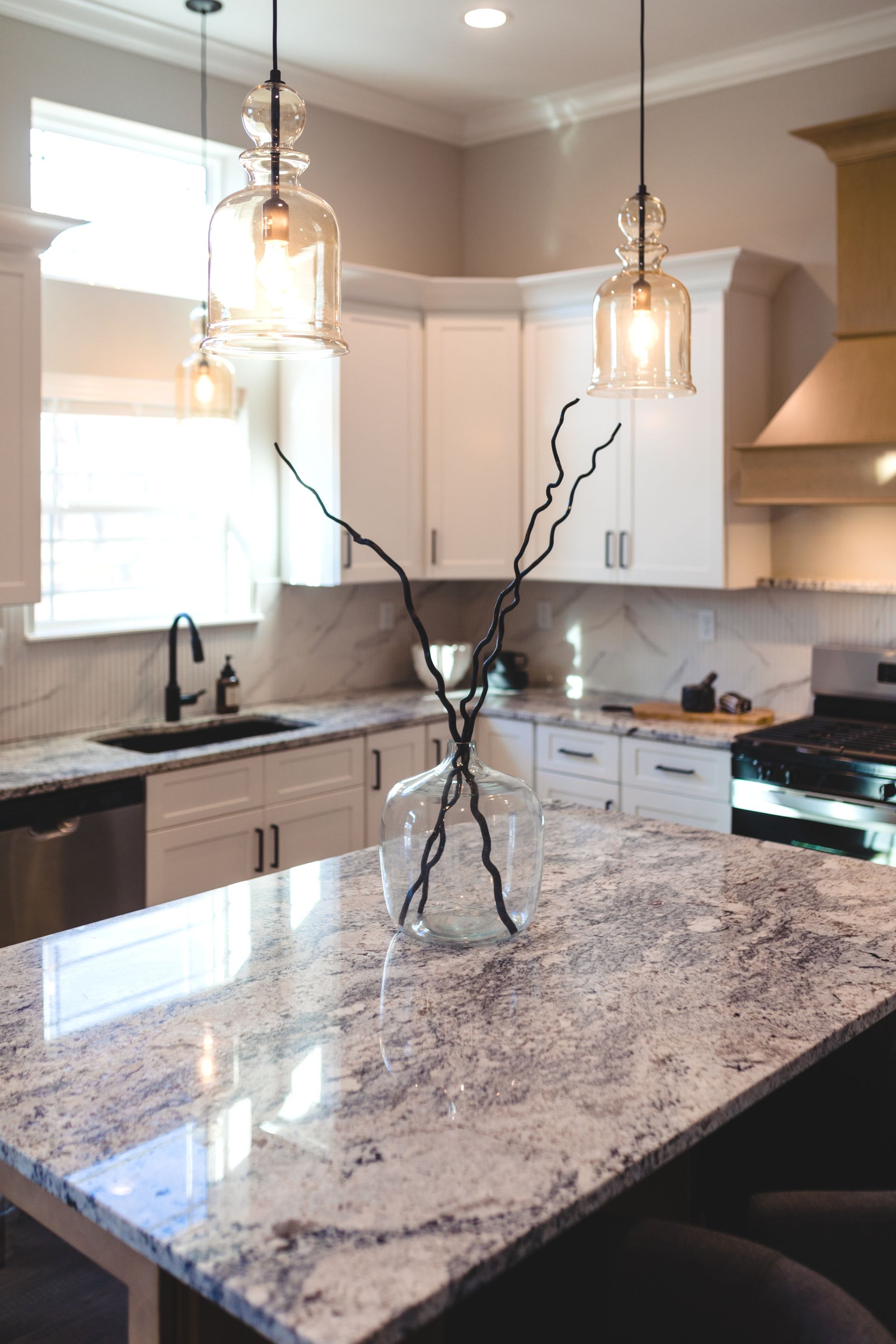 A kitchen with white cabinets and a marble counter top