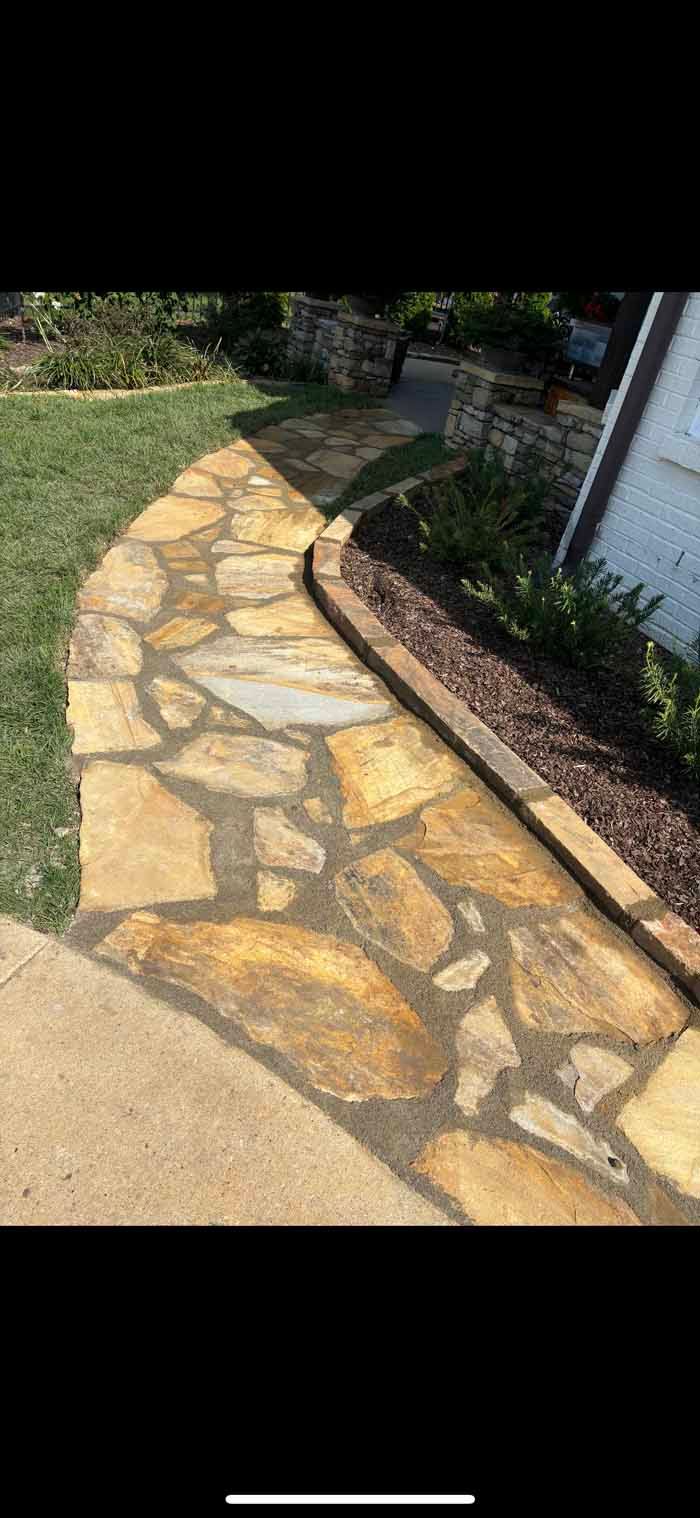 A stone walkway leading to a house in a yard.