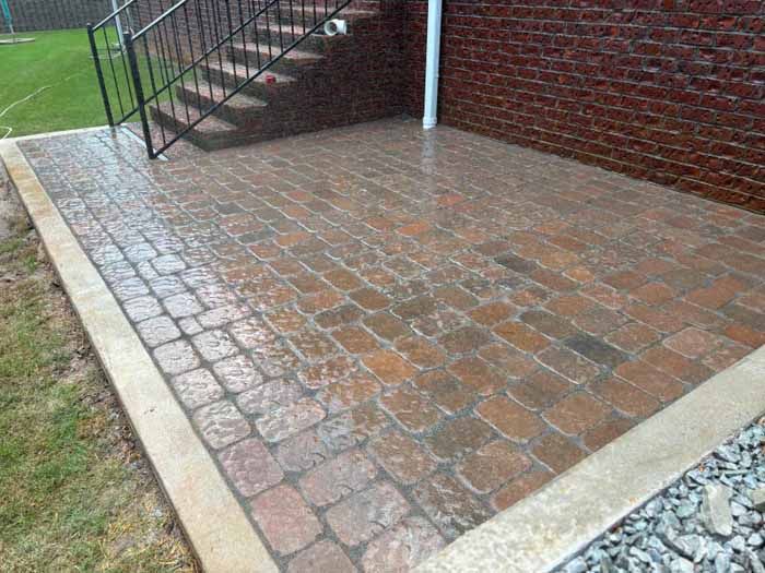 A brick patio with stairs leading up to it next to a brick wall.