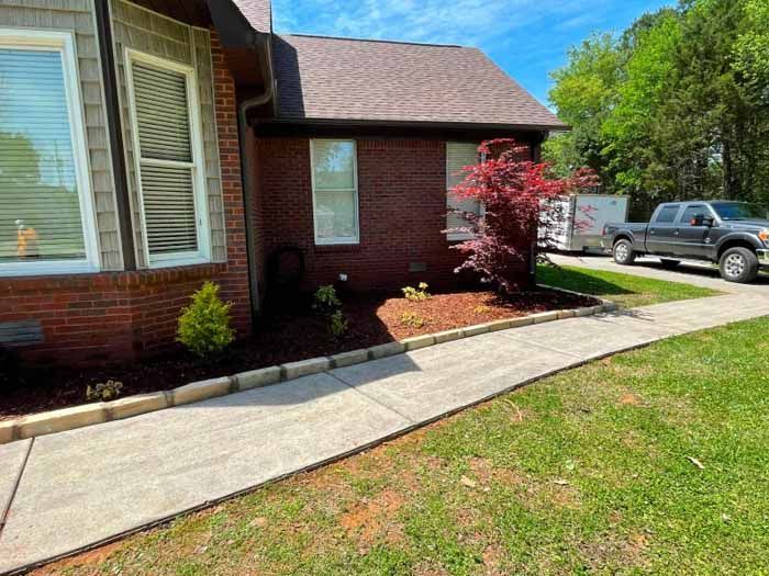 A brick house with a sidewalk and a truck parked in front of it.
