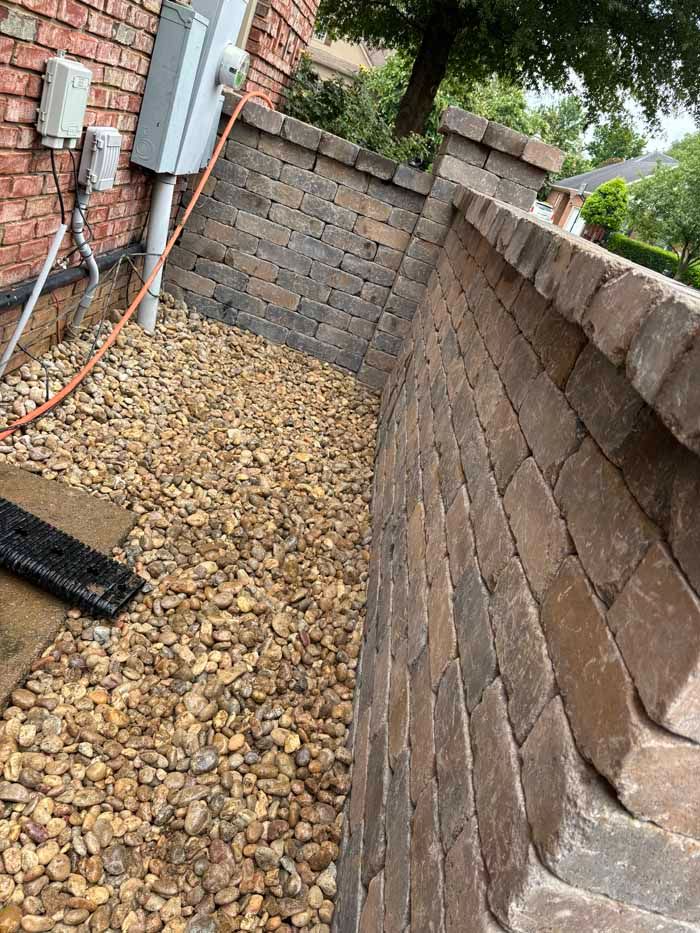 A brick wall with a hose attached to it next to a house.