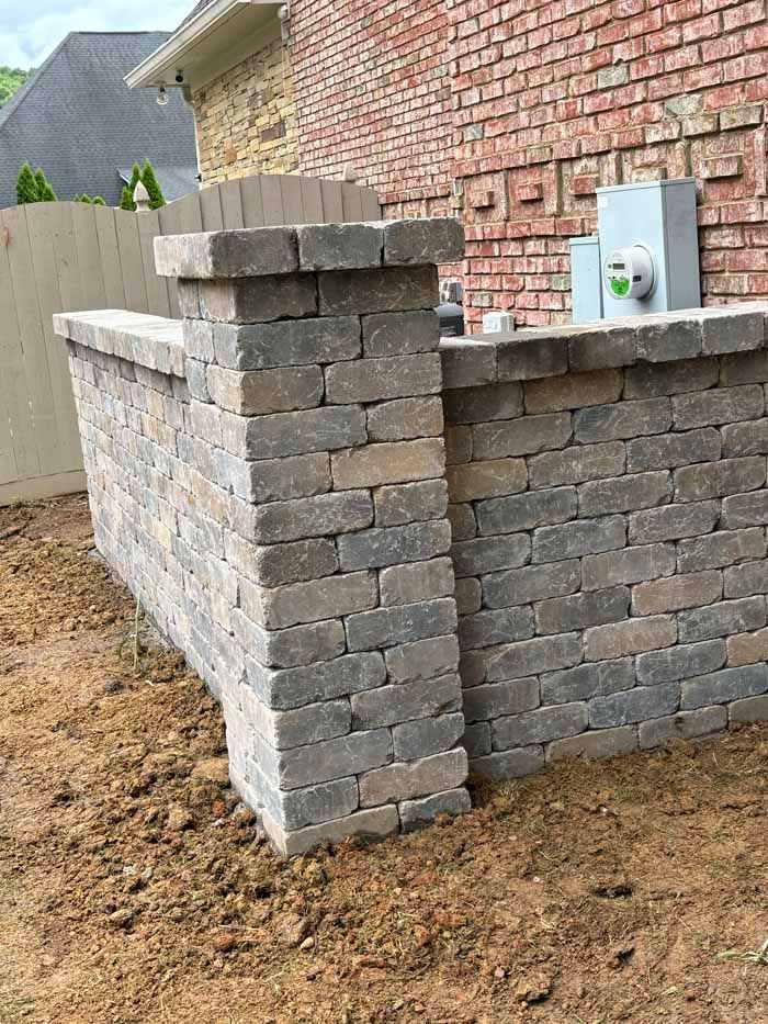 A brick wall is being built in the backyard of a house.