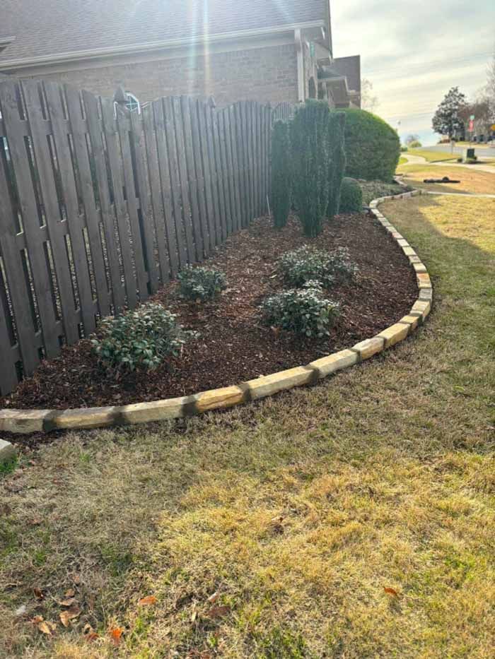 A wooden fence is surrounded by a lush green garden.