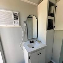 A bathroom with a sink , mirror and air conditioner.