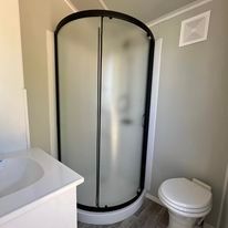 A bathroom with a toilet , sink and shower stall.